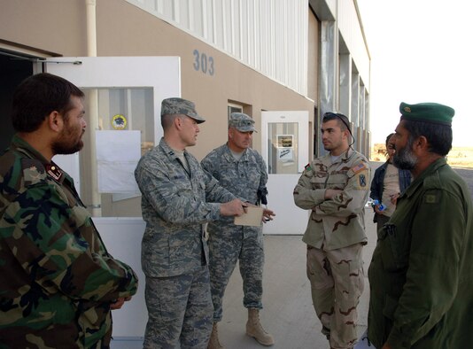 Capt. Eric McGreevy and Army Staff Sgt. Mark Reynolds speak to Afghan soldiers through an interpreter Nov. 20 Forward Operating Base Hero, Afghanistan. The training provided by the mentors is critical to keep the Afghan national army's fleet of more than 1,300 vehicles operational. Captain McGreevy and Sergeant Reynolds are Afghan National Army maintenance mentors. (U.S. Air Force photo/Staff Sgt. Mike Andriacco)