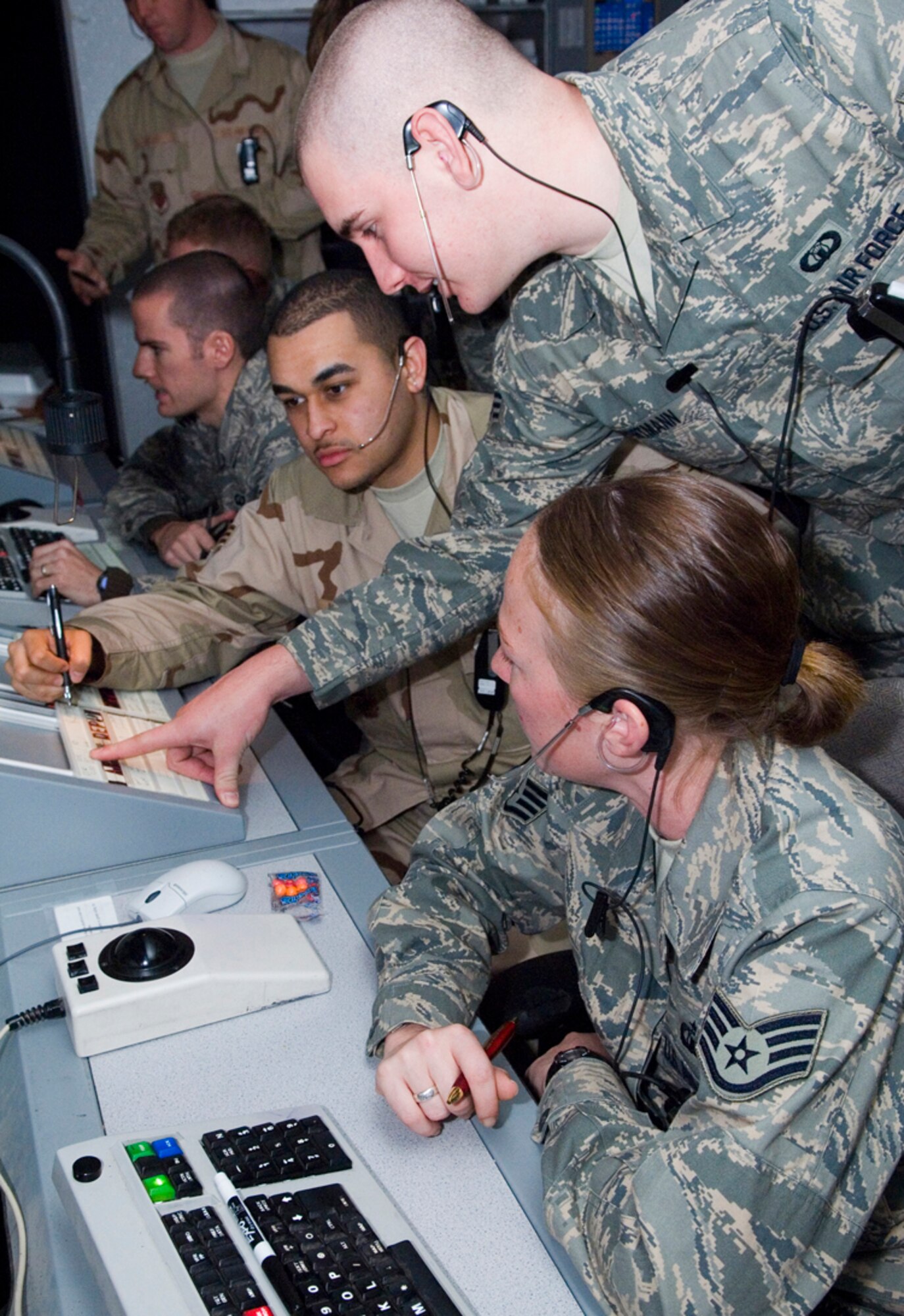BALAD AIR BASE, Iraq -- Senior Airman Aaron Portman, top, a 332nd Expeditionary Operations Support Squadron air traffic controller, working in the flight data position here, points out the altitude at which an inbound aircraft will be traveling to Senior Airman David Daniel, left, and Staff Sgt. Elizabeth Deem, both 332nd EOSS air traffic controllers working as approach control assistants. Airman Daniel is deployed from Royal Air Force Lakenheath, England, Airman Portman is from Dover Air Force Base, Del., and Sergeant Deem is deployed from Vance AFB, Okla. (U.S. Air Force photo/Senior Airman Travis Edwards)