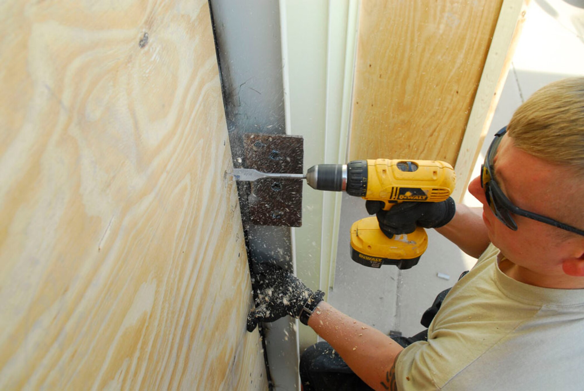 BALAD AIR BASE, Iraq -- Senior Airman James Altemus, a 557th Expeditionary REDHORSE Squadron structural technician, drills holes into a bay door for a temporary shelter here, Nov. 29. By pre-drilling, Airman Altemus can ensure that the hinges on the door fit properly once the door frame is in place.  Airman Altemus is deployed from Holloman Air Force Base, N.C. (U.S. Air Force photo/Staff Sgt. Joshua Garcia)