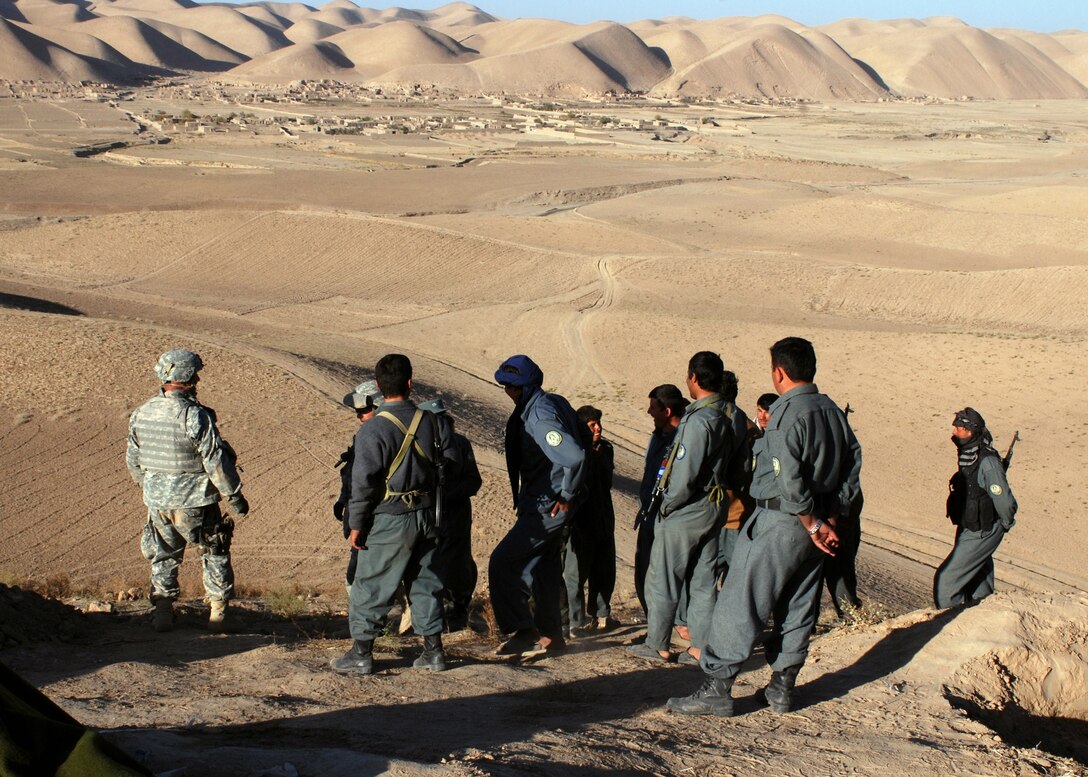 Army Capt. Stewart Gast gets a security update from an Afghan National Police officer at an observation post overlooking the Ring Road. Gast and others from his Police Mentoring Team stopped at the observation post to check on Afghan National Police deployed during an operation against insurgents in northwest Faryab province. Photo by Petty Officer 1st Class David M. Votroubek, USN