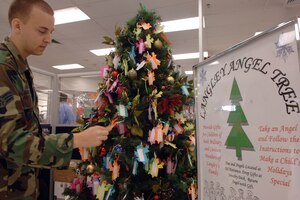 LANGLEY AIR FORCE BASE, Va. -- Senior Airman Justin Hunniecutt, 1st Communications Squadron, chooses a tag from the Langley Angel Tree Nov. 30. The Angel Tree program, which provides gifts for children of military and civilian family members that might not otherwise receive gifts, runs until Dec. 14. The tree is located at the Langley Main Exchange entrance. People who would like to donate can take an angel tag from the tree, purchase the requested gifts and bring the tag and gifts to the BX jewelry counter. (U.S. Air Force photo/Airman 1st Class Vernon Young)