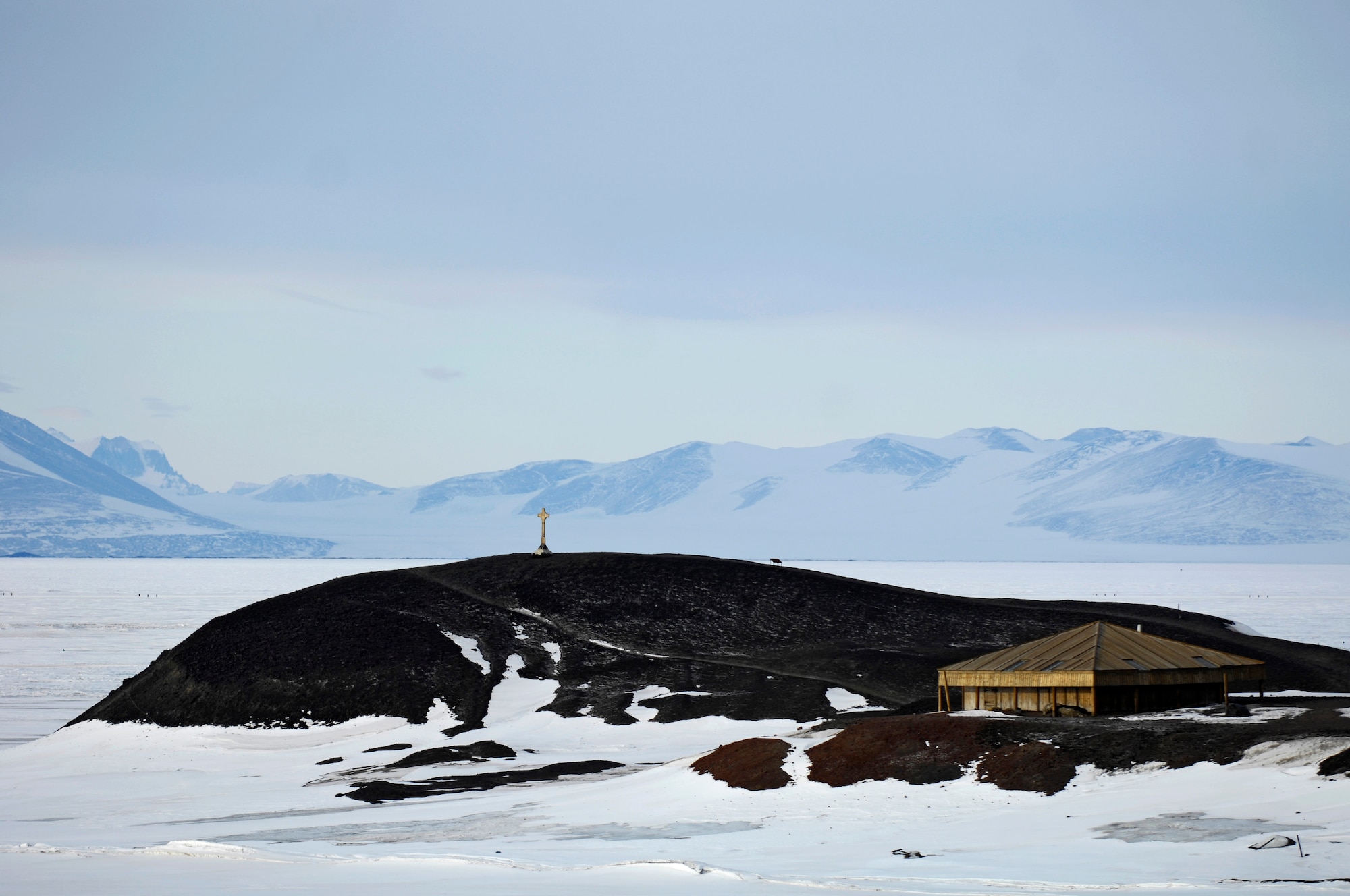 Scott’s Hut and a cross monument sit near McMurdo Station, Antarctica Nov. 26, 2007. Scott’s Hut was erected in 1911 by the British Antarctic Expedition of 1910-1913 led by Robert Falcon Scott. The cross is an historic monument commemorating T. Vince of the British Antarctic Expedition of 1901-1904 who lost his life in the vicinity in March 1902. The hut and monument are preserved by the freezing temperatures and dry climate of Antarctica. McMurdo Station is the largest community in Antarctica and a science research center operated by the United States through the United States Antarctic Program a branch of the National Science Foundation.  Today the 13th Air Force-led Joint Task Force Support Forces Antarctica, Operation Deep Freeze, provides operational and logistics support to the Natoinal Science Foundation and U.S. Antarctic Program. The operation began in 1955.  (U.S. Air Force photo/Tech. Sgt. Shane A. Cuomo)