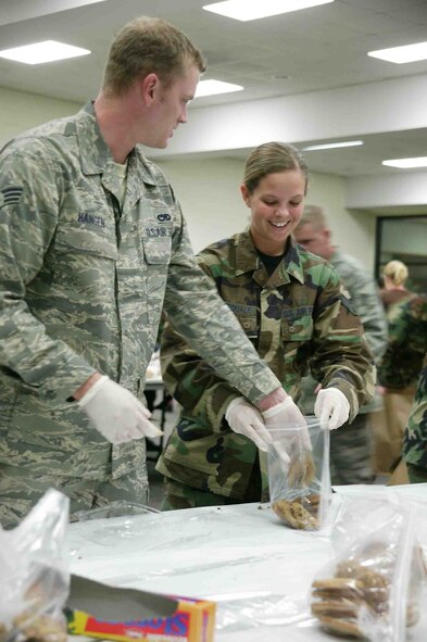 SHAW AIR FORCE BASE, S.C. --  Senior Airmen Matthew Hangen, 20th Equipment Maintenance Squadron, and Brooke Dipasquale, 20th Medical Operations Squadron, bag up cookies during the Shaw Cookie Drive Nov. 29 at the Community Activities Center. The Airman's cookie drive, sponsored by the Enlisted Spouses Club and the Officer and Civilian Spouses Club, received more than 60,000 cookies this year from local community and base volunteers. The cookies are distributed to Airmen across Shaw and to deployed Airmen and Soldiers as well. (U.S. Air Force photo/Staff Sgt. John Gordinier)
