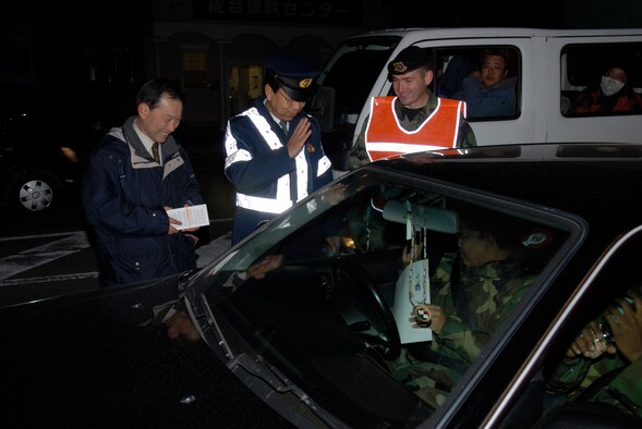 MISAWA AIR BASE, Japan -- (Left to Right) Tsuka Machio, Senior Liason to the Misawa City Police, Chief Toshio Nara of the Misawa City Police, and Maj. Scott Sanford, 35th Security Forces Squadron commander, hand out winter safety fliers to residents here on Nov. 28, 2007.  The fliers covered several hazzards of winter driving as well as other safety information.  (U.S. Air Force photo by Senior Airman Laura R. McFarlane)
