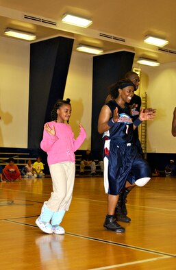 Nia Wilson, 8, and Lade Majic from the Harlem Ambassadors dance after Nia won a game of catch at an exhibition game between the Ambassadors and Misawa Jets Nov. 28. Nia won a basketball signed by the Ambassadors as a prize. (U.S. Air Force photo by Airman 1st Class Eric Harris)