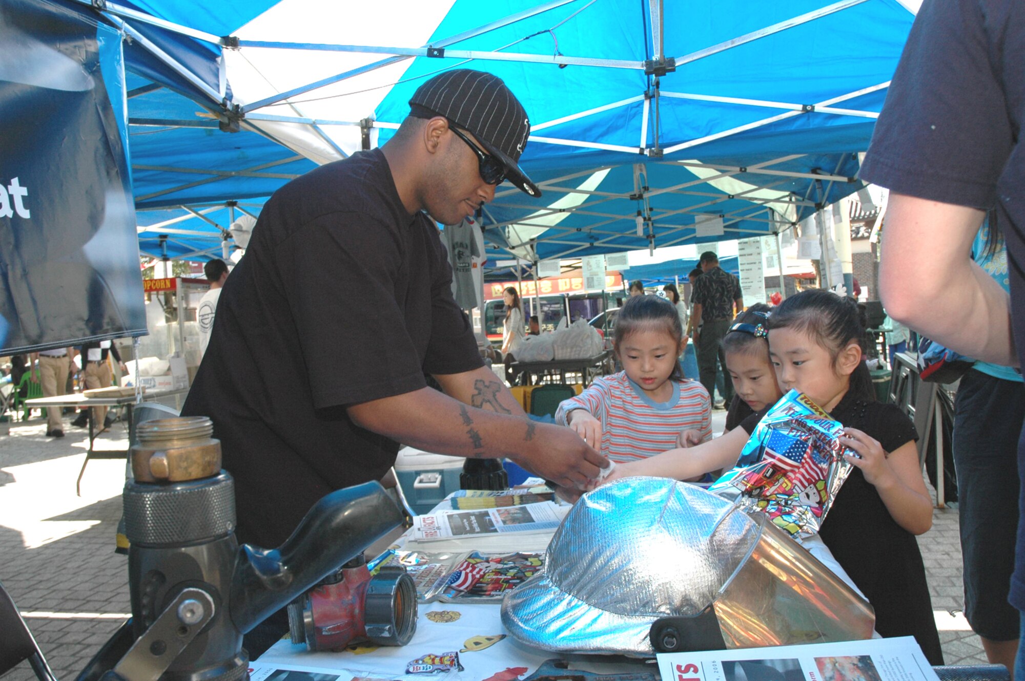 SONGTAN, Republic of Korea --  An Airmen from the 51st Civil Engineering Squadron fire department gives stickers to children at the fire department booth during the Korean/American Friendship Festival here Sept. 23, 2006. The 2007 festival takes place Oct. 13 and 14 in the Shinjang Shopping Mall just outside the main gate here. (U.S. Air Force photo by Tech. Sgt. Michael O'Connor)
