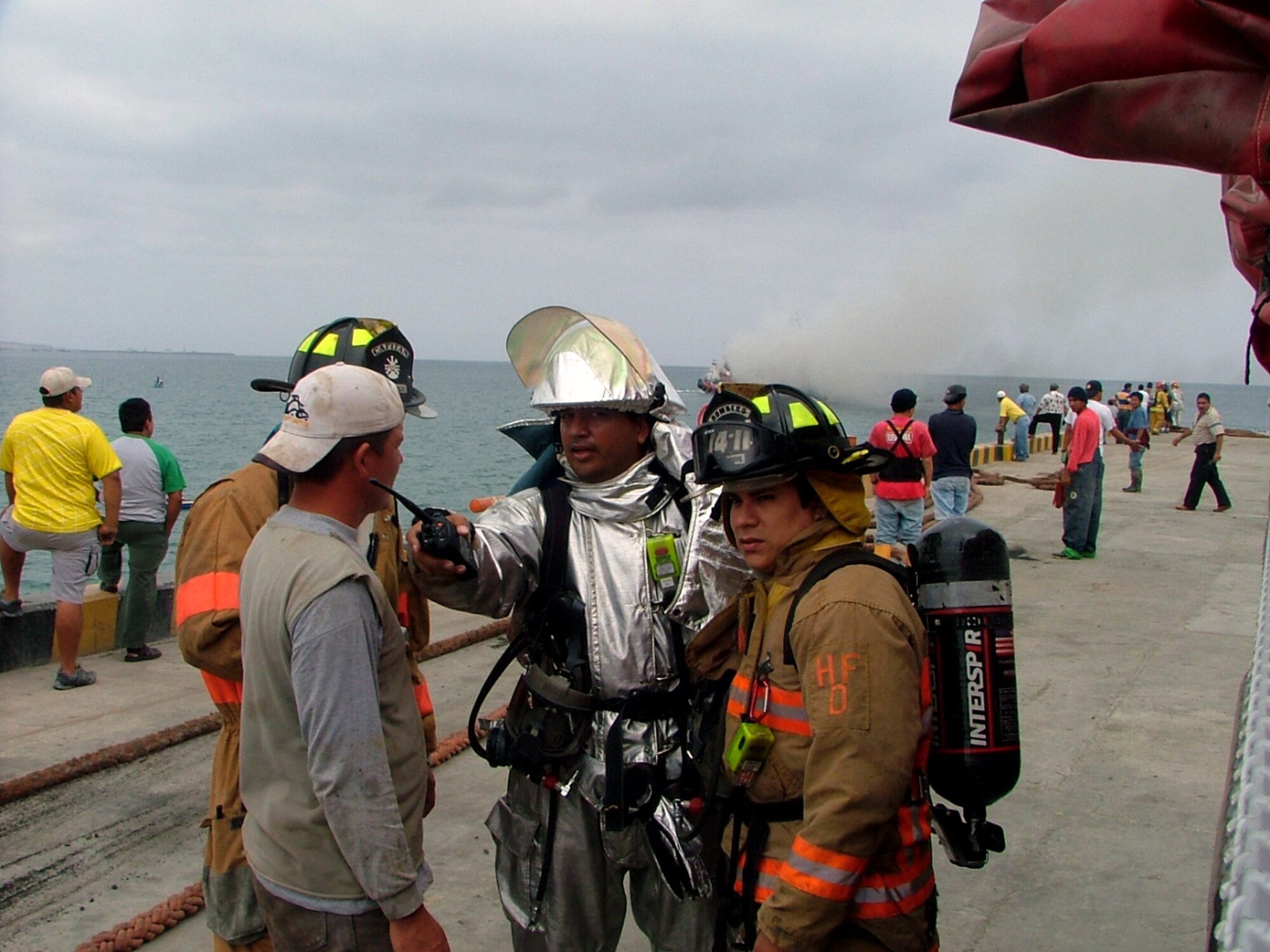 Firefighter Fabrizio Recalde (in silver) talks with members of the local Manta, Ecuador, fire department Sept. 26 as they plan their strategy for putting out a fire on a local fishing boat. Forward Operating Location Manta firefighters assisted the local authorities in putting out the fire. (U.S. Air Force Photo/2nd Lt. Naomi Evangelista) 
