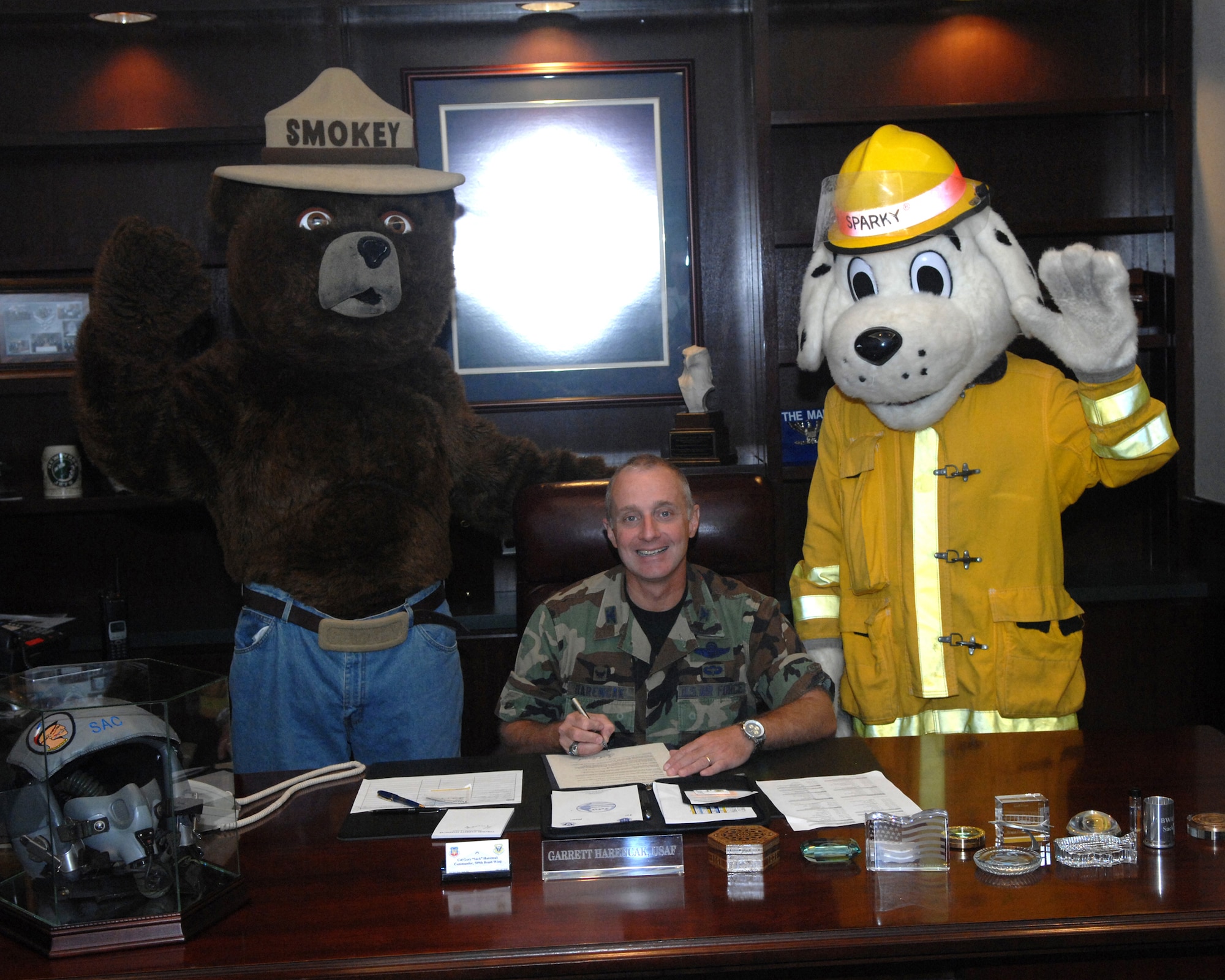 Col. Garrett Harencak, 509th Bomb Wing commander, signs this year's fire proclamation as Smokey the bear and Sparky standby Sept. 29. Fire Prevention Week has been declared as Oct. 7-13, and the Whiteman Fire and Emergency Services Flight has planned several events to further educate the base populace. (U.S. Air Force photo/Airman 1st Class Cory Todd) 