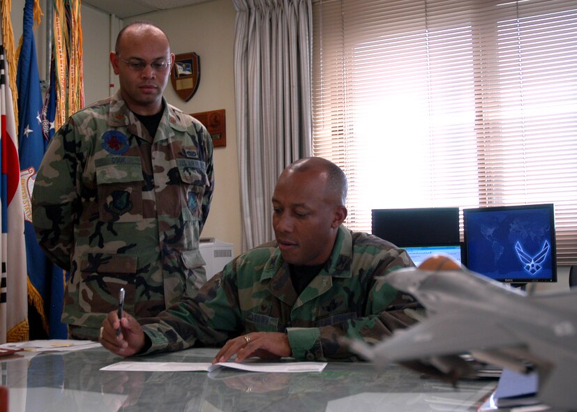 KUNSAN AIR BASE, South Korea— Colonel CQ "Wolf" Brown, 8th Fighter Wing commander, fills out a Combined Federal Campaign form here Oct. 1 as Maj. Joseph Cook, installation CFC project officer looks on. The CFC allows federal employees the opportunity to support causes that matter the most. (U.S. Air Force photo/Staff Sgt. Araceli Alarcon)                                                                