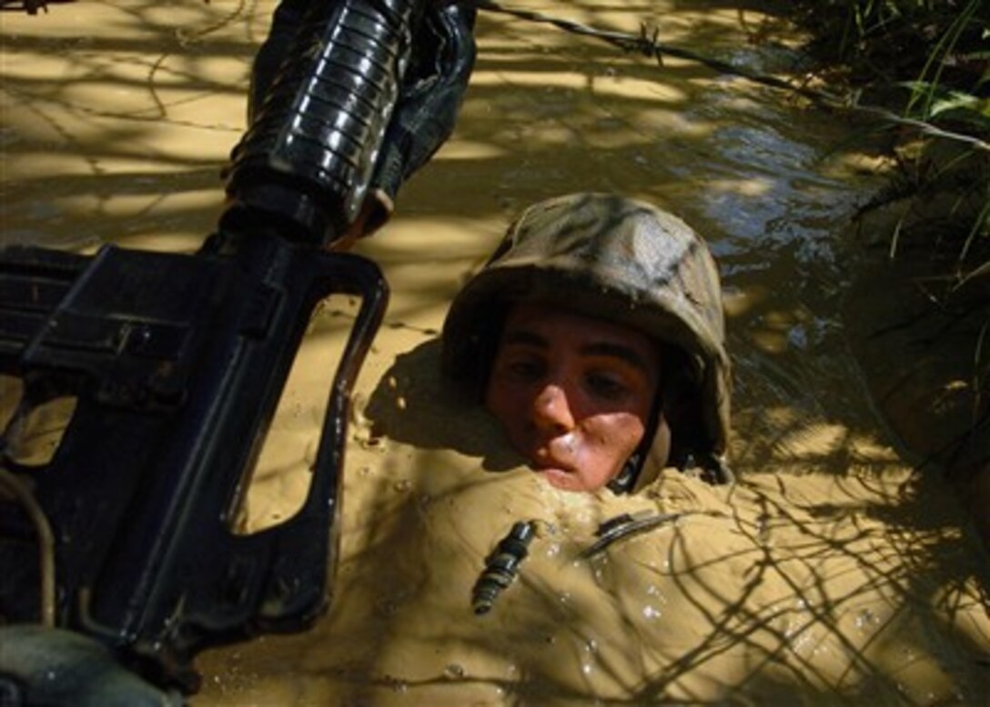 A U.S. Navy Seabee with Naval Mobile Construction Battalion 7 negotiates a mud-filled trench during a jungle warfare training exercise in Okinawa, Japan, hosted by U.S. Marines assigned to Jungle Warfare Training Command on Sept. 27, 2007.  