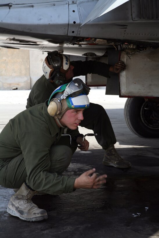 AL ASAD, Iraq - Lance Cpl. Anthony Polimeni, an ejection seat mechanic with Marine All-Weather Fighter Attack Squadron 225, uses hand signals to communicate over the engine sounds of an F/A-18 "Hornet" as he and Cpl. Jeffrey Bloomer, a powerline mechanic, troubleshoot a problem on the flightline, Oct. 2.