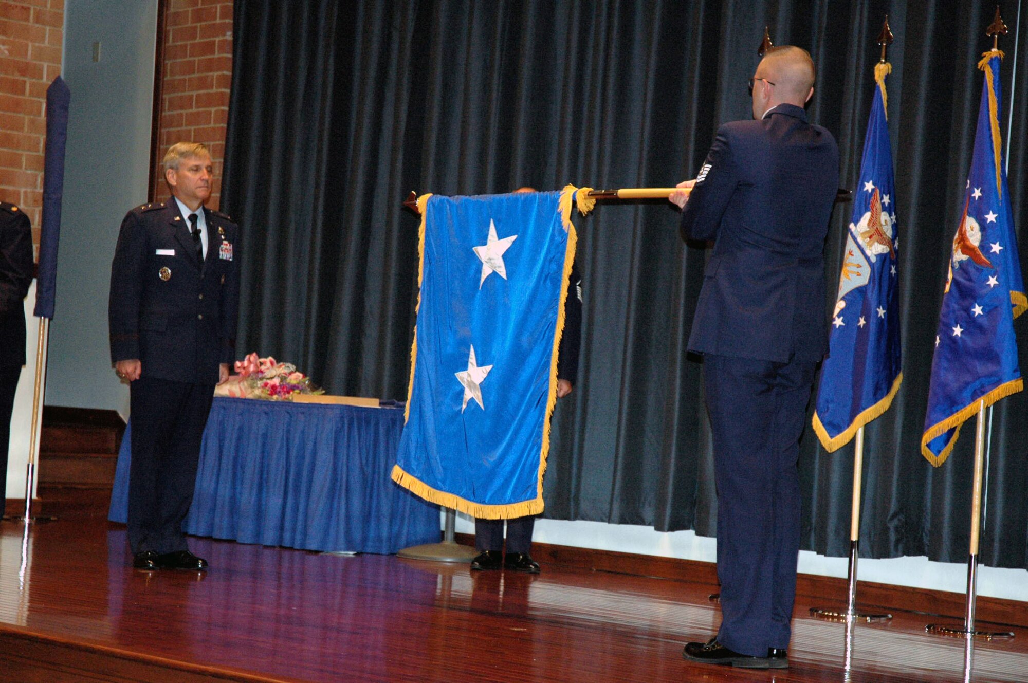 Tech. Sgt. Ryan Holmes, U.S. Air Force Expeditionary Center Mobility Operations School, unfurls the new two-star personal flag in honor of Maj. Gen. Kip Self, USAF EC Commander, during General Self's promotion ceremony Oct. 1 at the Center.  (U.S. Air Force Photo/Tech. Sgt. Scott T. Sturkol)