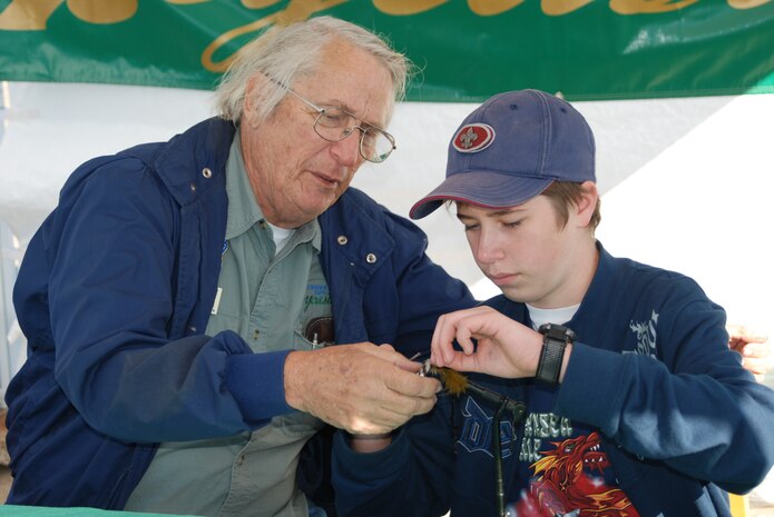 Pete Peterson of Granite Bay Flycasters, assists Ethan Cavender, 12, a Boy Scout with Shingle Springs Boy Scout, with a fly fishing lure. (Photo by Airman 1st Class Robert Biermann)