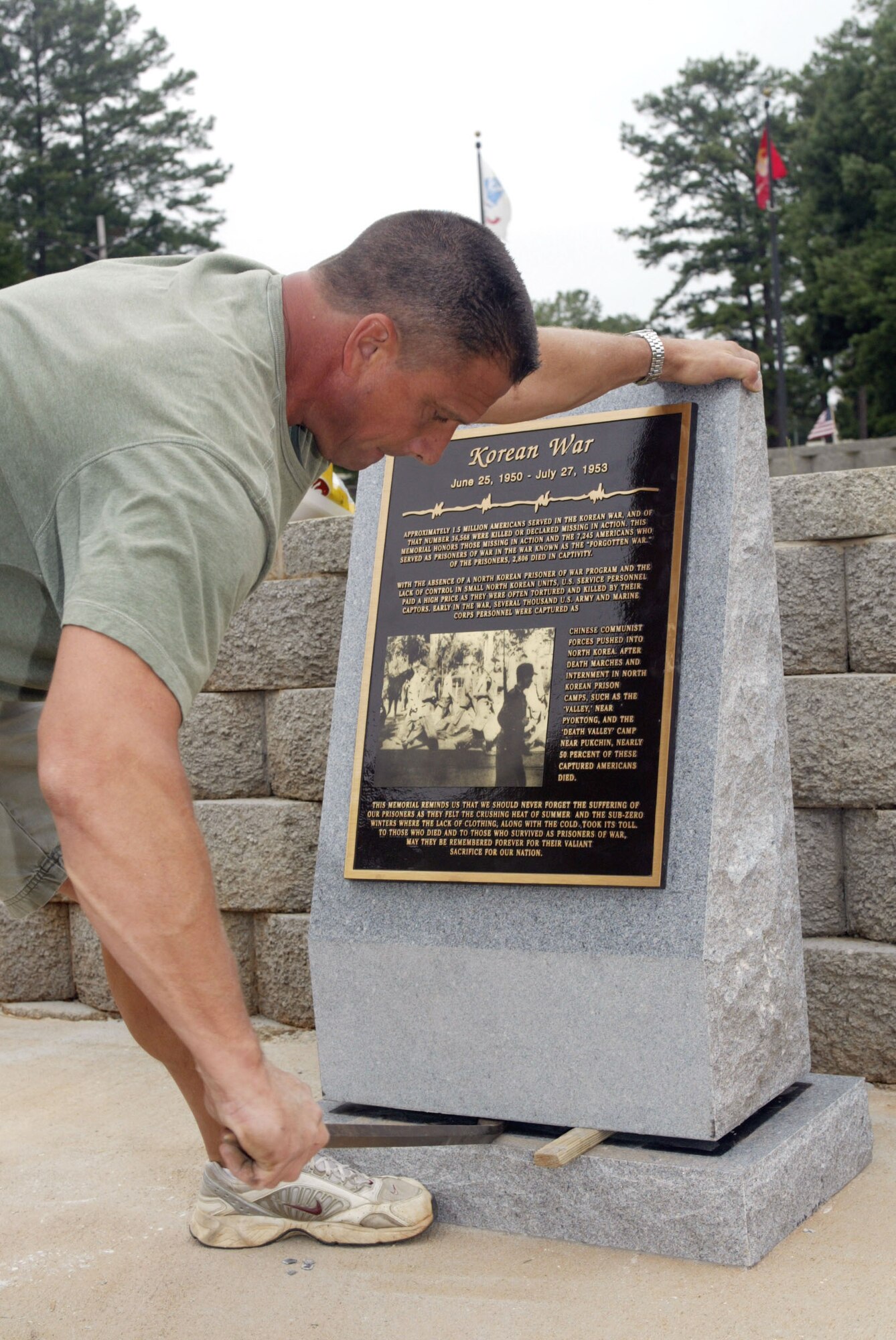 A volunteer works at installing the new Korean War memorial at the Dobbins POW/MIA park. The installation took place directly after the living memorial ceremony and tree planting. The monument is one of four planned for the park. (U.S. Air Force photo/Don Peek)