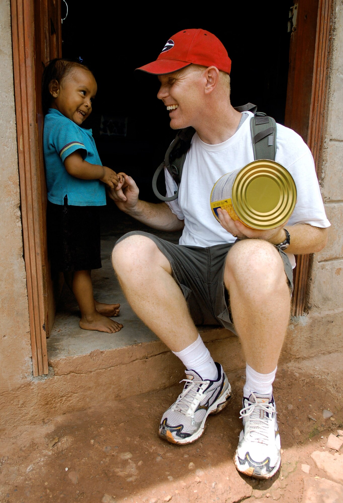 Chaplain (Capt.) Chad Bellamy plays with a young Honduran girl during a break on a nearly five-mile hike to deliver supplies to families living in the mountains near Comayagua, Honduras. The Joint Task Force-Bravo chaplain organized the trip, which delivered 450 pounds of food to the village of Mata  De Platano. (U.S. Air Force photo/Staff Sgt. Austin May)