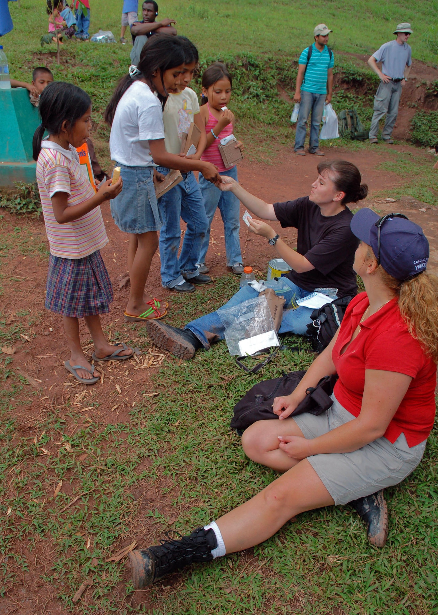 Technical Sergeants Angel Roush and Diane Strohm hand out stickers to a group of young Honduran girls during their lunch break Sept. 29 near the mountains of Comayagua. The two were participating in a nearly five-mile hike that was organized by the Joint Task Force-Bravo Chapel from Soto Cano Air Base, Honduras, to deliver food to families in the mountains. The NCOs are part of the JTF-Bravo Medical Element. (U.S. Air Force photo/Staff Sgt. Austin May)