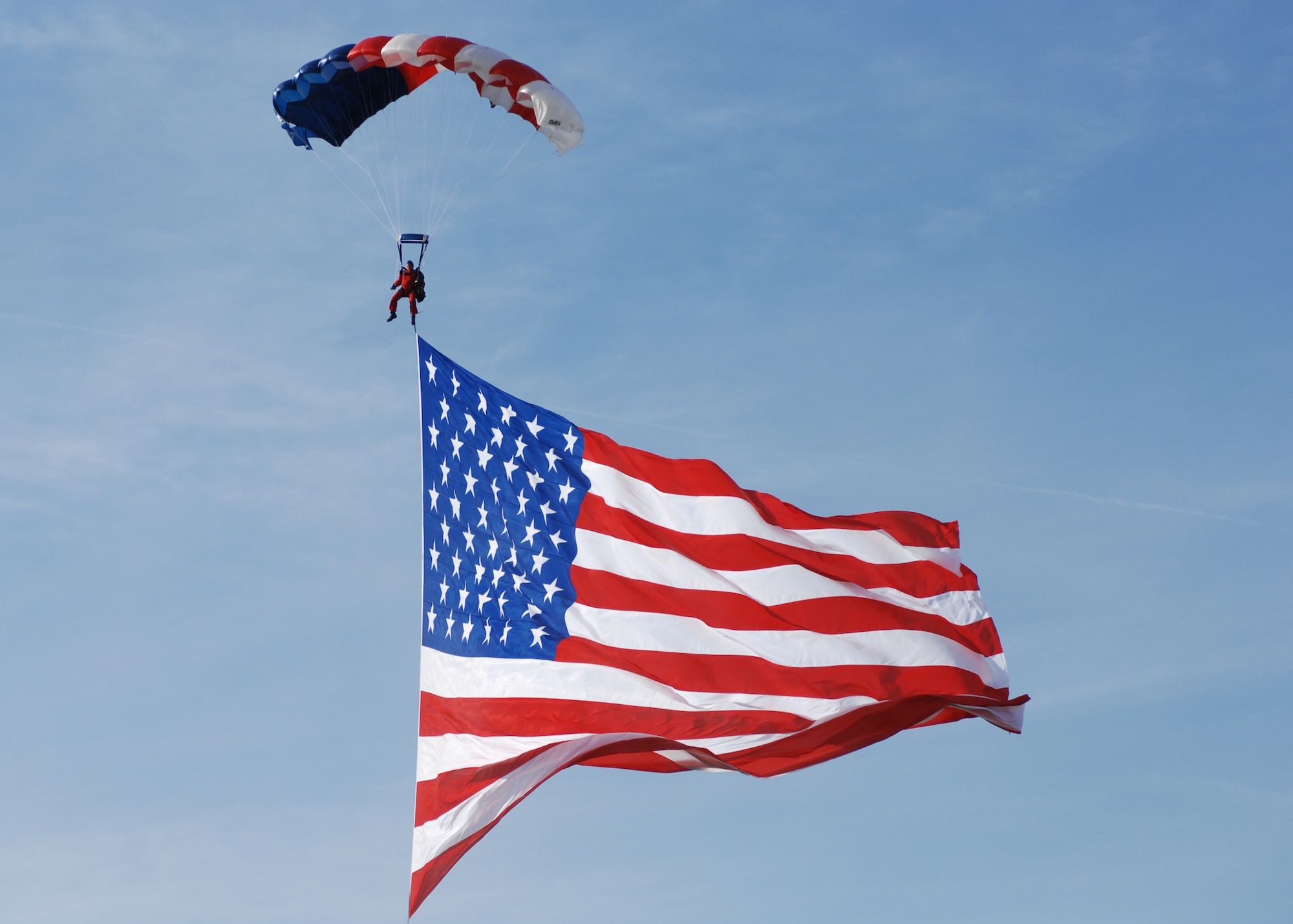 A parachuter drifts to the ground with the american flag during the opening ceremony for the Gathering of Mustands and Legends. (Air Force photo by Senior Airman Amanda Cain)
