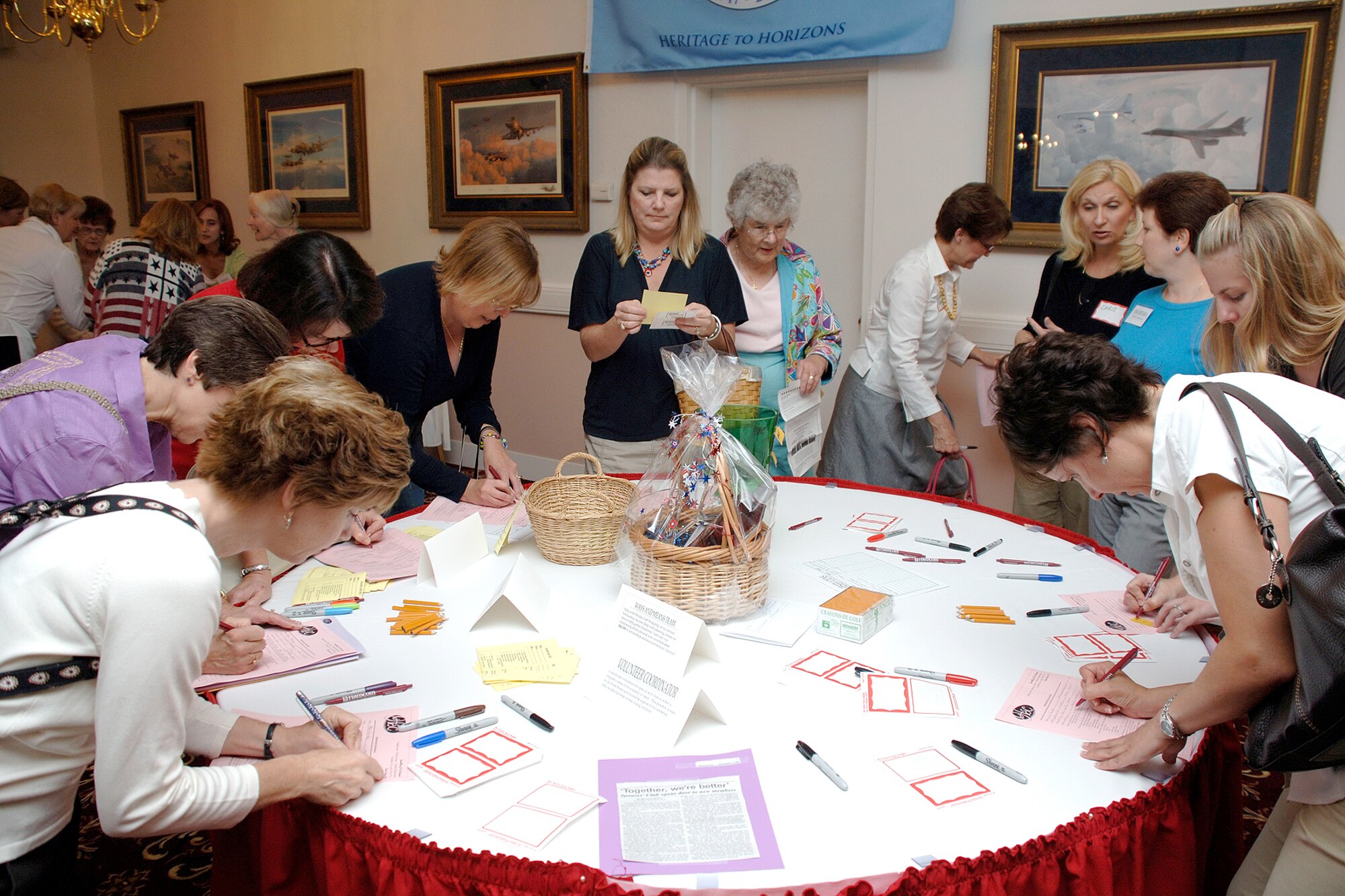 A group of women gather around a table to sign up for volunteer positions, fill out name tags and enter to win door prizes during the Hanscom Spouses’ Club kick-off event Sept. 25. The theme of the event was, “Common Ground: Together, we’re better.” Members of the Hanscom Spouses’ Club, formerly known as the Hanscom Officers’ Spouses’ Club, voted in May to include more Hanscom spouses in their membership. The club is now open to spouses of all military members, to include the Guard and Reserves, regardless of service or rank. (U.S. Air Force photo by Jan Abate.)