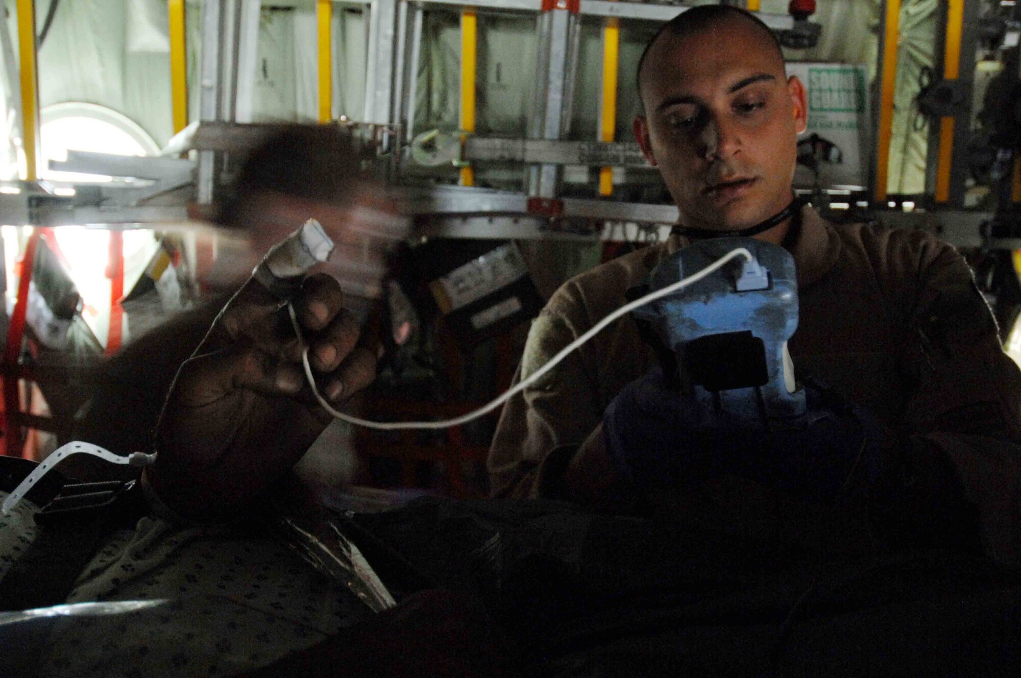 Staff Sgt. Josh Green, a medical technician with the 455 Expeditionary Aeromedical Evacuation Flight, Bagram Air Base, Afghanistan, monitors the oxygen content and heartbeat of the Afghan patient that he is transporting.  The 455EAEF utilizes C-130 aircraft to provide quick aeromedical evacuation response to injured Coalition forces, as well as Afghan combatants and civilians.