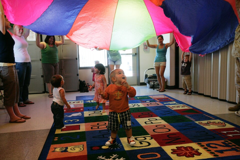 With the help of parents, Levi Free, Lily Ledbetter and Olivia Garansvay, rush under the parachute in excitement during a Kindermusik class Wednesday.