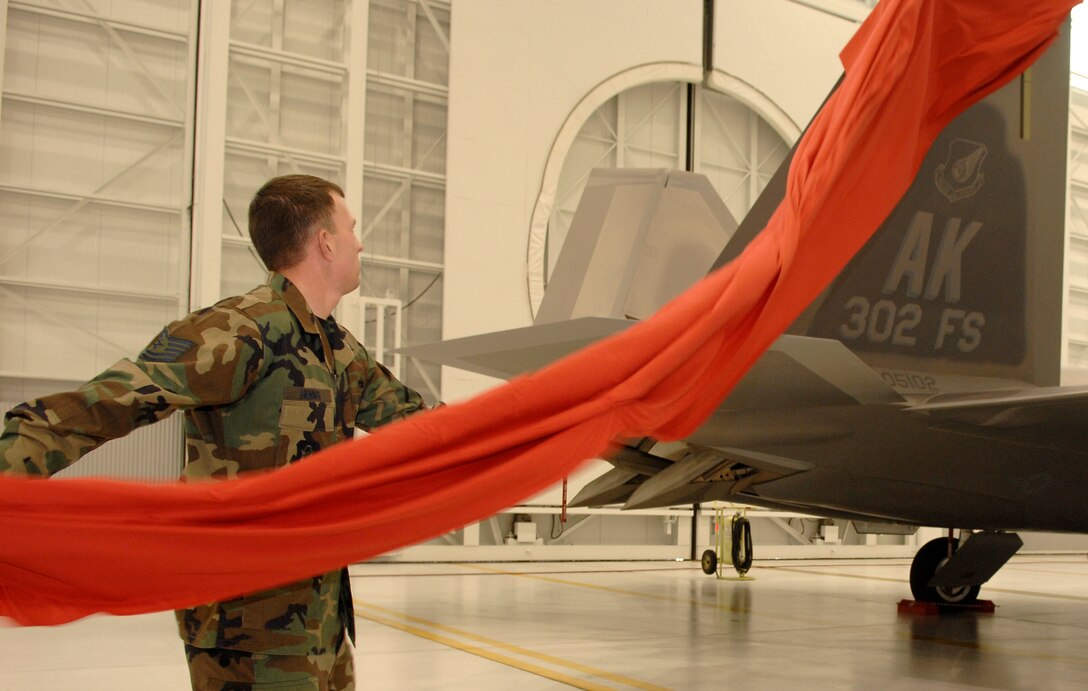 Tech. Sgt. Paul Hennig, 477th Fighter Group F-22 crew chief, unveils the newly painted 302nd Fighter Squadron tail. The 477th Fighter Group, and its subsequent squadrons, became the first and only Reserve F-22A Raptor unit in the Air Force during the activation ceremony at Elmendorf Air Force Base, Alaska, Tuesday. (U.S. Air Force photo by Master Sgt. Chance Babin)