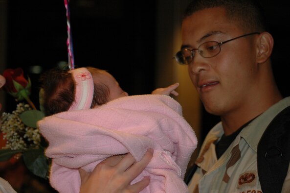 HILL AIR FORCE BASE, Utah -- Senior Airman Calvin Miranda, 75th Security Forces Squadron, holds his 2-month old daughter for the first time since returning from Iraq Oct. 2. He was among 45 Airmen who returned from a seven-month deployment to Bucca, Iraq. (Air Force photo by Capt. Genieve David) 