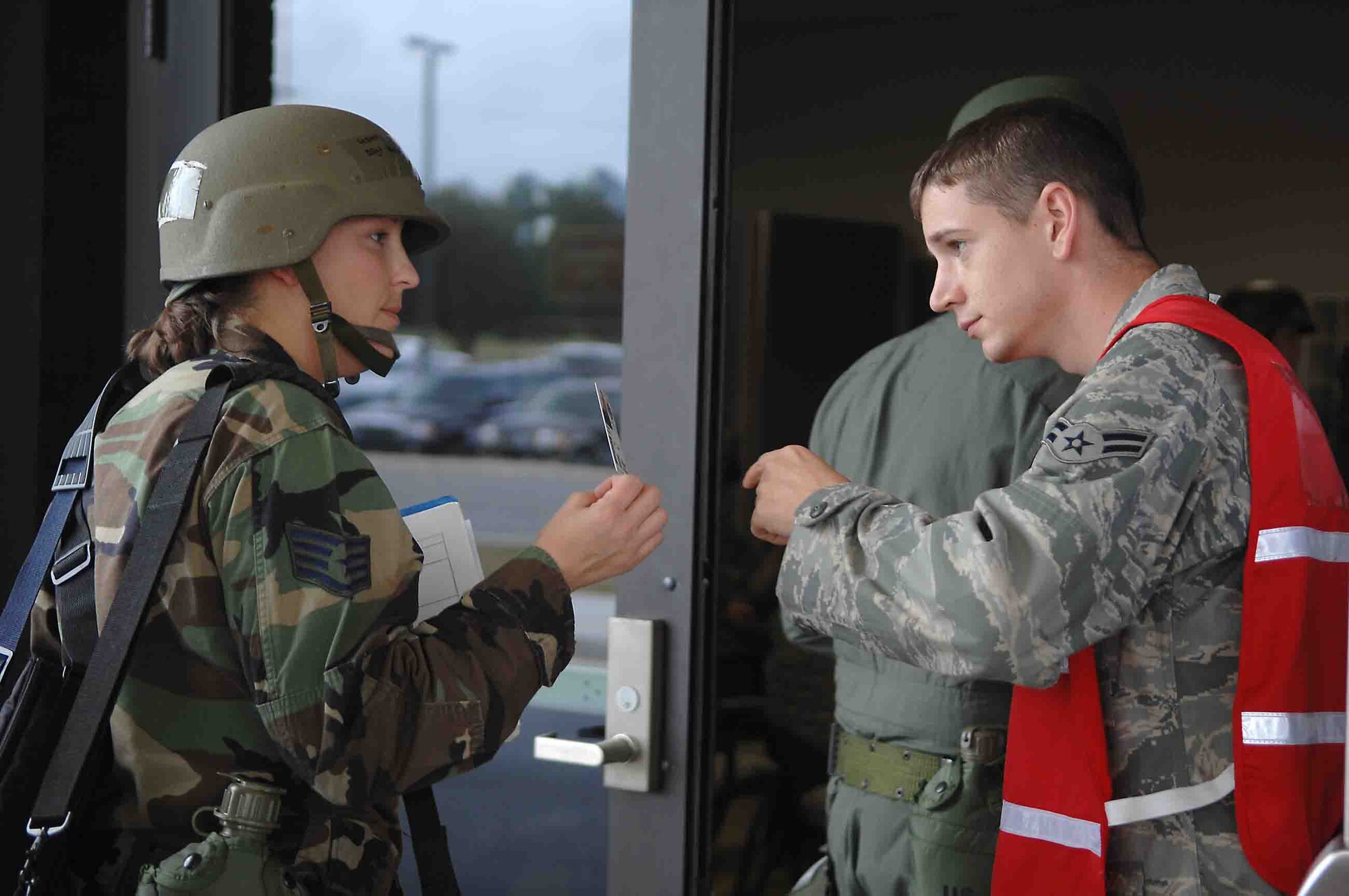 SHAW AIR FORCE BASE, S.C. -- Airman 1st Class David Harvey, 20th Communications Squadron Ground Radio technician, checks the identification card of Staff Sgt. Krista Houser, 55th Fighter Squadron Airfield Management, as she enters the Chandler Deployment Processing Center to ensure security is maintained during an Operational Readiness Exercise Oct. 4. Operational Readiness Exercises help Airmen prepare for deployments to combat environments. (U.S. Air Force photo/Airman 1st Class Matthew Davis)