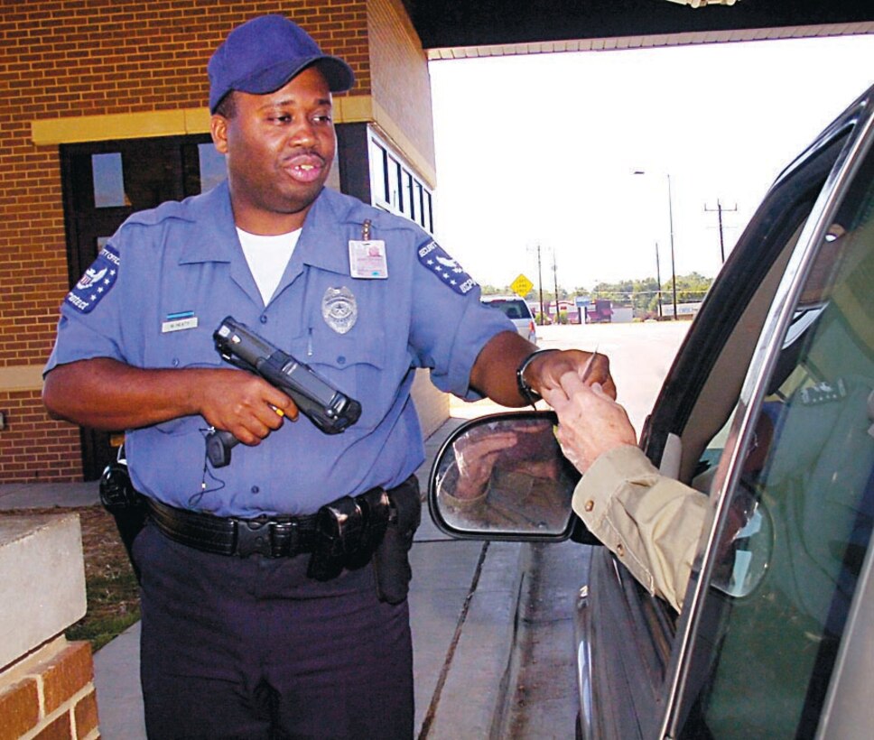 U.S. Protect officer Marc Heath checks an incoming visitor's identification during the early morning hours at the Main Gate of Andrews AFB, Md. on Sept. 28. (US Air Force/Bobby Jones)