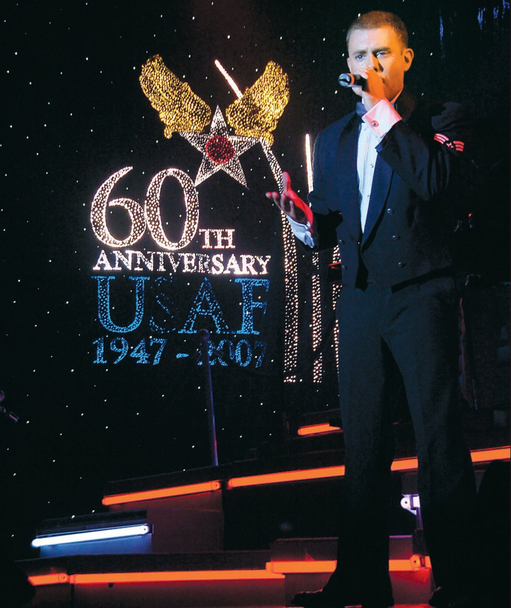 Senior Airman Nicholas Amari sings "God Bless the USA" by country western recording artist,  Lee Greenwood during the conclusion of the Tops in Blue show Sept. 28.  Airman Amari is a security forces journeyman assigned to the 122nd Security Forces Squadron, Fort Wayne Air National Guard, IN.(US Air Force/Bobby Jones)