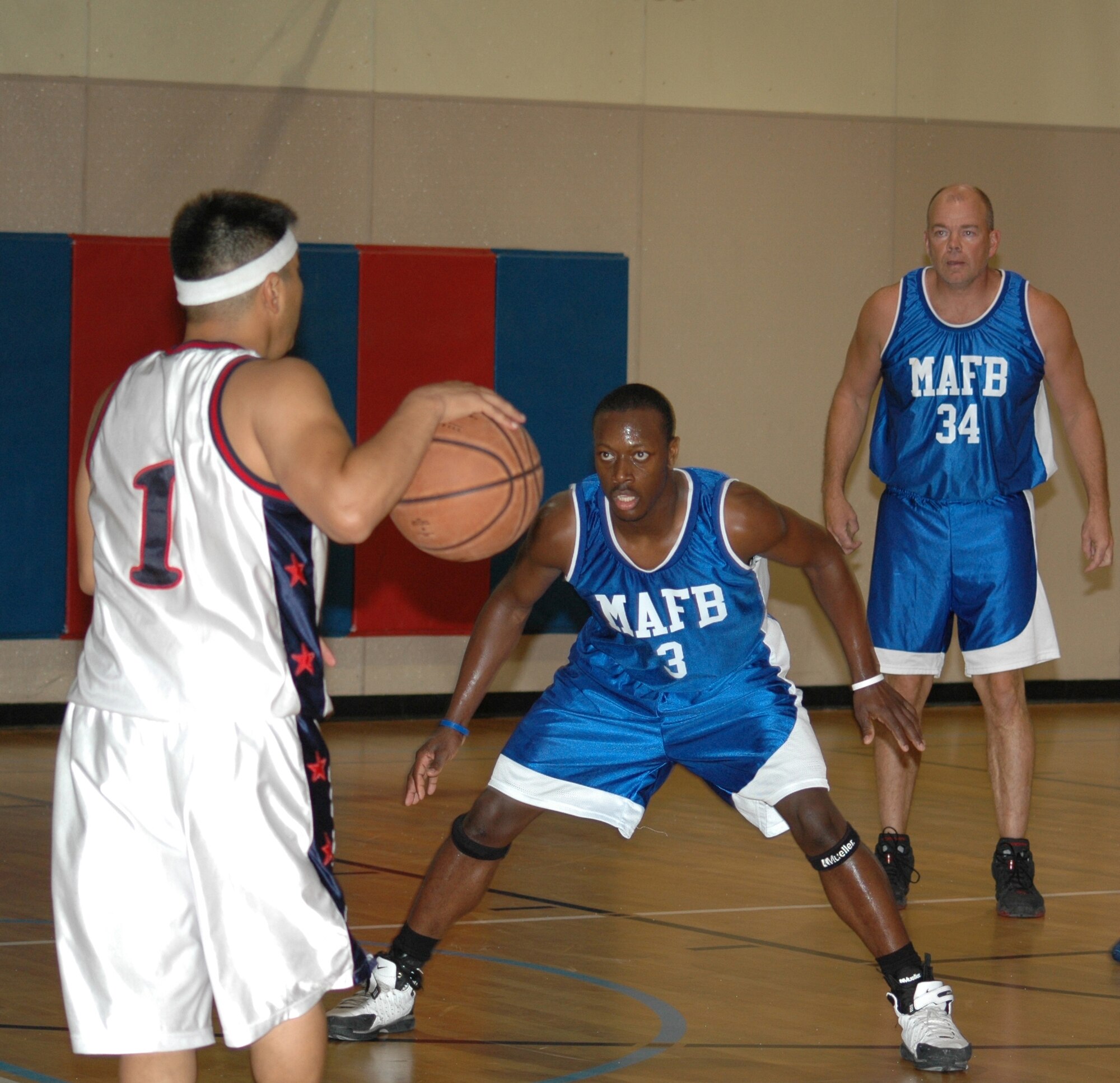Malmstrom "B" team guard Maurice Jones, #3, watches his Nellis opponent, Ulises Sanchez, intently as he tries to defend his next move. Malmstrom forward Stewart Reynolds also studies the action. Nellis won this first meeting between the two teams during the Fall Basketball Classic 52-47, (U.S. Air Force photo/Airman 1st Class Emerald Ralston)