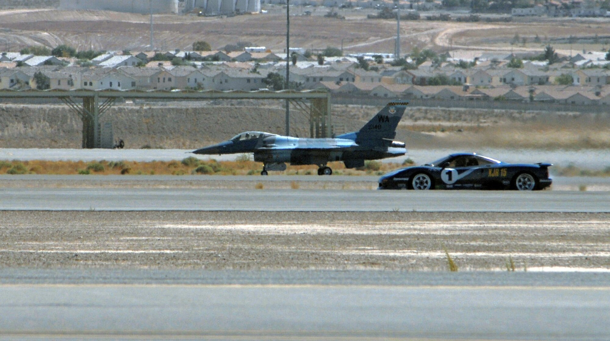 An F-16 Fighting Falcon, one of the Air Force's most powerful single-engine fighters, races an XJR15 Jaguar down a one-mile stretch of runway Sept. 29 at Nellis Air Force Base, Nev . The F-16 won the race, one of three special events held during the two-day Nellis Autocross. (U. S. Air Force photo/Airman 1st Class Nadine Barclay)