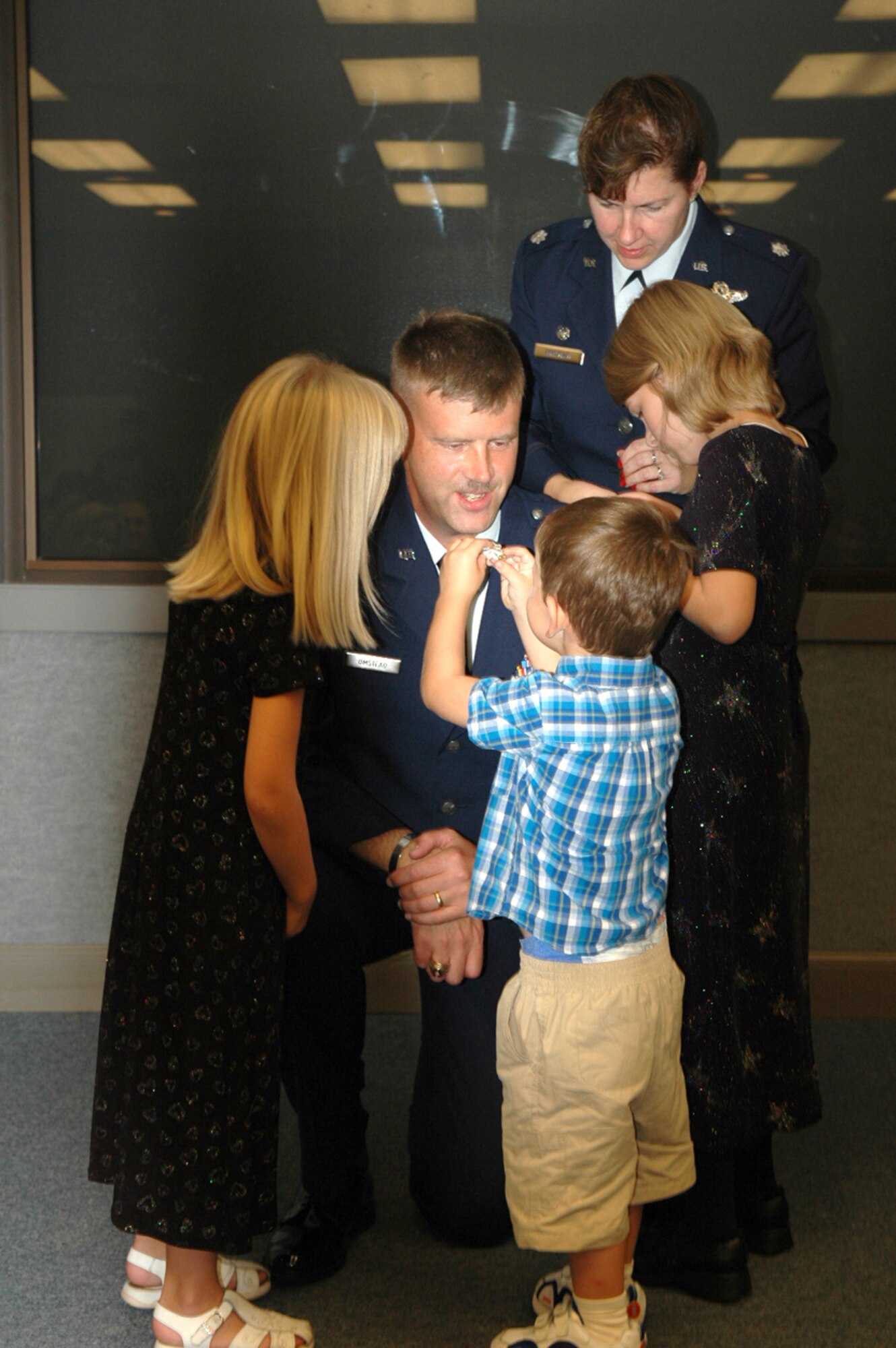 TYNDALL AIR FORCE BASE, Fla. -- Lt. Col. David "DavO" Omstead, 53d Weapons Evaluation Group Standardization and Evaluation Officer, comes down to his children’s level as they pin on his new lieutenant colonel rank. Cecilia, 6, Andrew, 3, and Katharine, 8, and their mom, Lt. Col. Barbara Omstead, 81st Range Control Squadron commander, all make sure the new rank is in place during the pin on ceremony Sept. 28. (US Air Force photos/ Senior Airman Kristen Gonzalez)