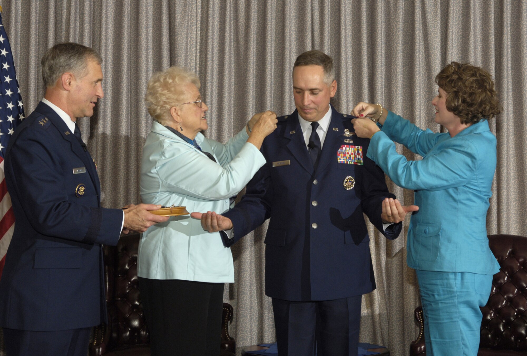 Maj. Gen. James Hawkins, 18th Air Force commander, watches Col. Rick Martin’s, former 305th Air Mobility Wing commander, mother Geri Martin, and wife, Barbara, pin on his brigadier general star during his frocking ceremony here Oct. 2. General Martin relinquished command of the 305 AMW to Col. Balan Ayyar during a change-of-command ceremony here Oct. 2. (U.S. Air Force photo/Kenn Mann)