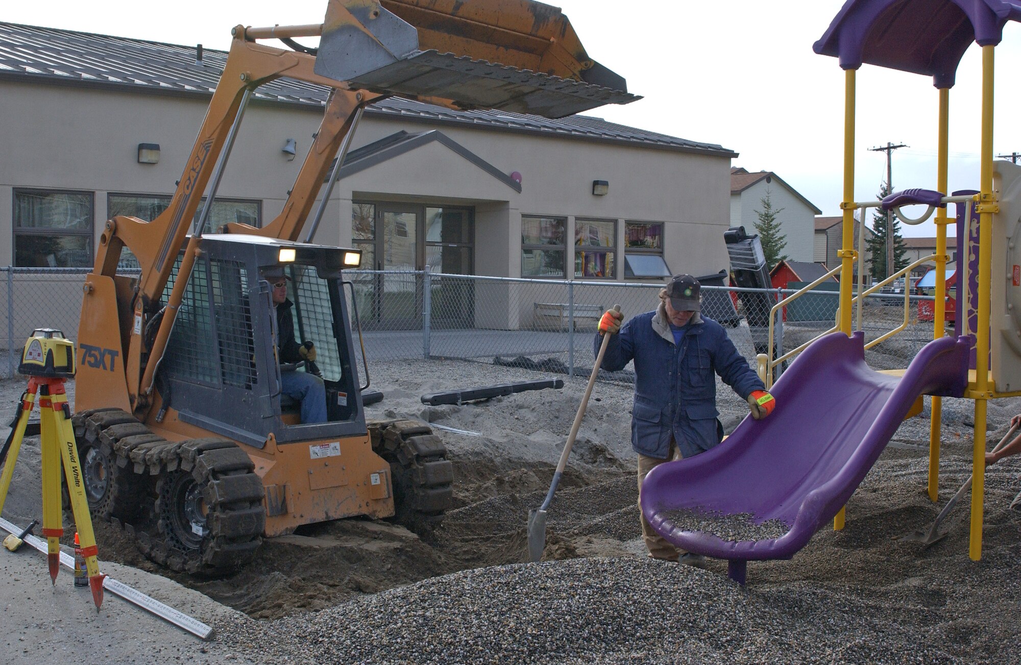 EIELSON AIR FORCE BASE, Alaska--Shane Denning, Trost Construction employee, operates a Skidster to dump rocks in a playground pit while Rich Goodson, also of Trost Construction, waits to spread them out Oct. 5 at the Child Development Center. The new playground is expected to be finished within two weeks. (U.S. Air Force photo by Airman 1st Class Nora Anton)                               