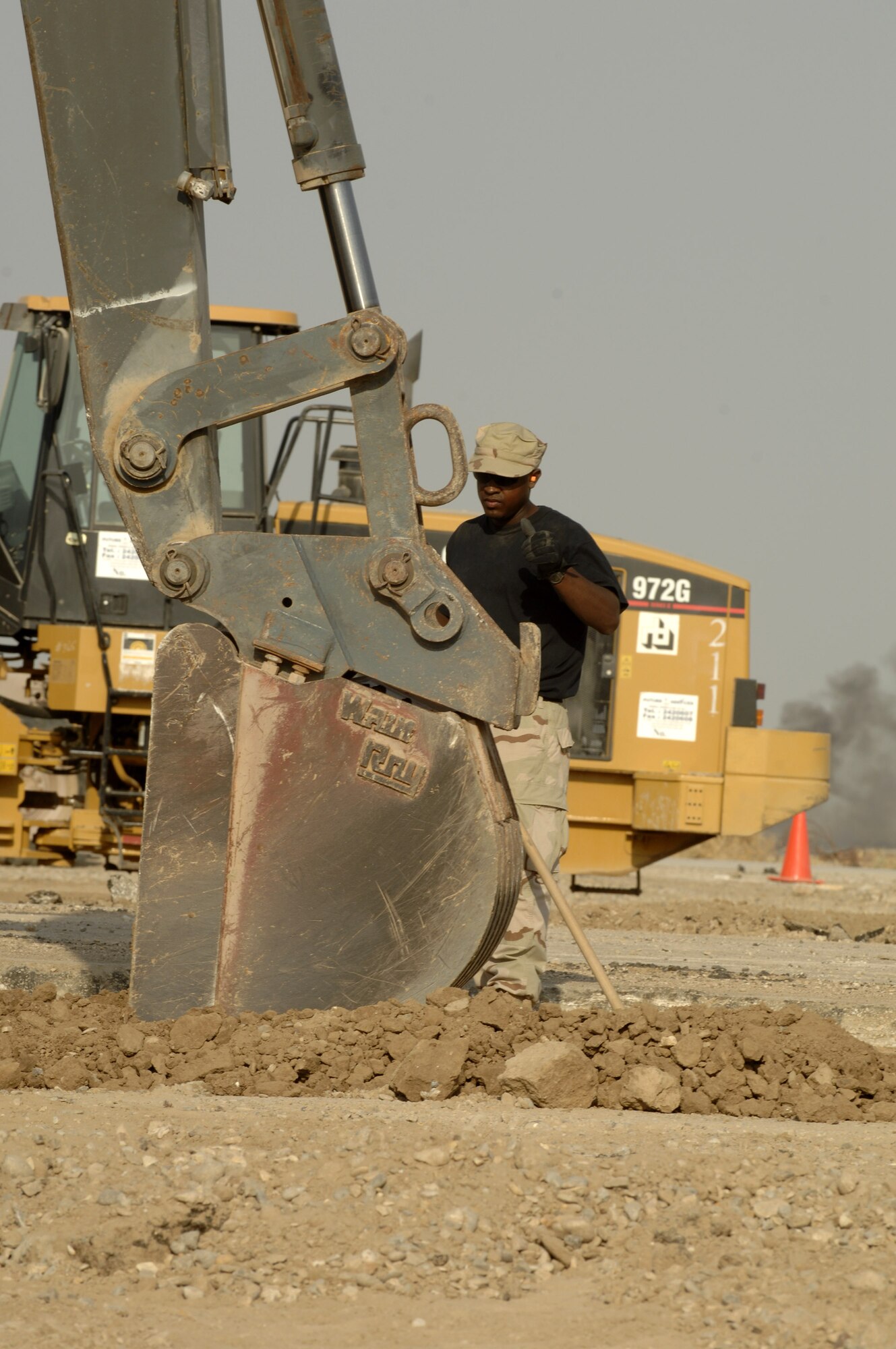 Senior Airman Paul Davis guides the excavator that is digging a trench Oct. 3 for concrete footers for sun shades being installed on the Ali Base, Iraq, flightline.  Airman Davis and other Airmen in the 407th Civil Engineer Squadron are working around the clock to build the sun shades by November.  (U.S. Air Force photo/Airman 1st Class Jonathan Snyder) 