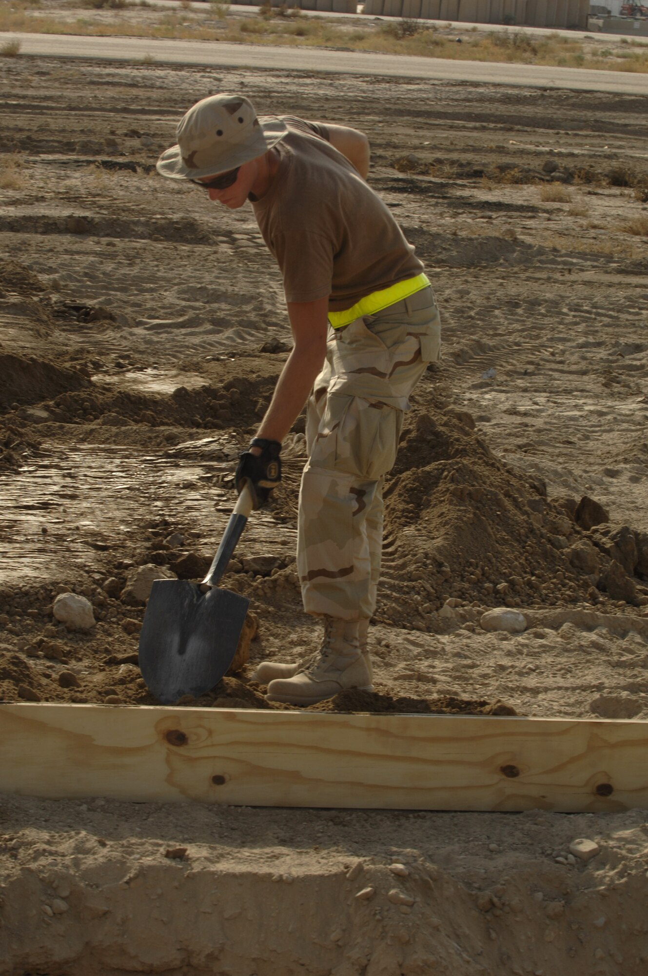 Airman 1st Class Dustin Haycox packs dirt around a wooden form Oct. 3 to hold it in place prior to pouring a concrete footer for sun shades being installed on the Ali Base, Iraq, flightline.  Airman Haycox and other Airmen in the 407th Civil Engineer Squadron are working around the clock to build the sun shades by November.  (U.S. Air Force photo/Airman 1st Class Jonathan Snyder) 