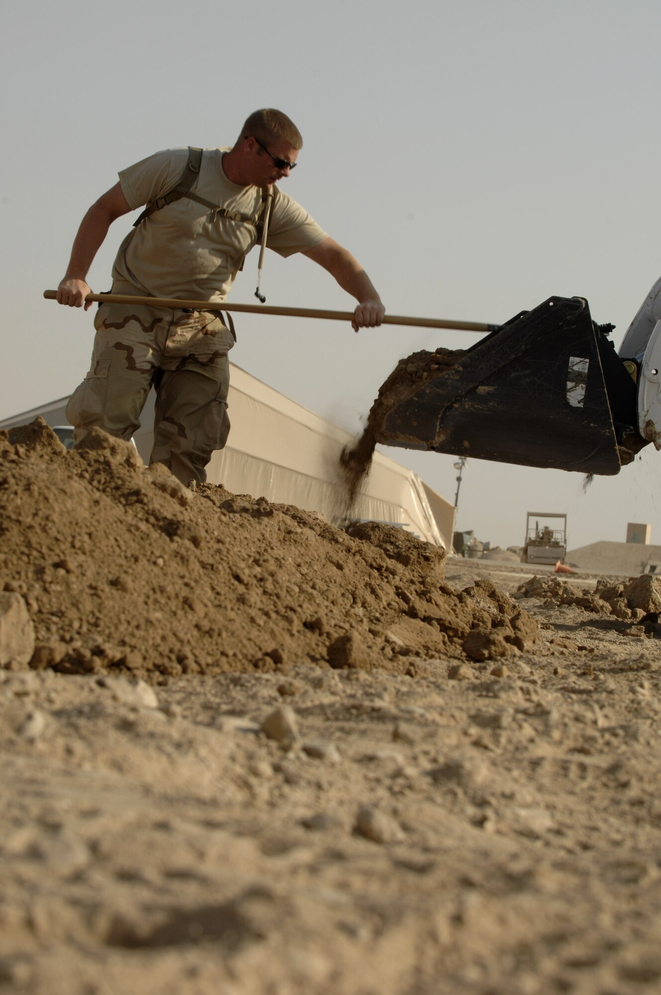 Senior Airman Mathew Mcdearmon spreads dirt Oct. 3 to help hold a wooden form in place prior to pouring a concrete footer for sun shades being installed on the Ali Base, Iraq, flightline.  Airman Mcdearmon and other Airmen in the 407th Civil Engineer Squadron are working around the clock to build the sun shades by November.  (U.S. Air Force photo/Airman 1st Class Jonathan Snyder) 