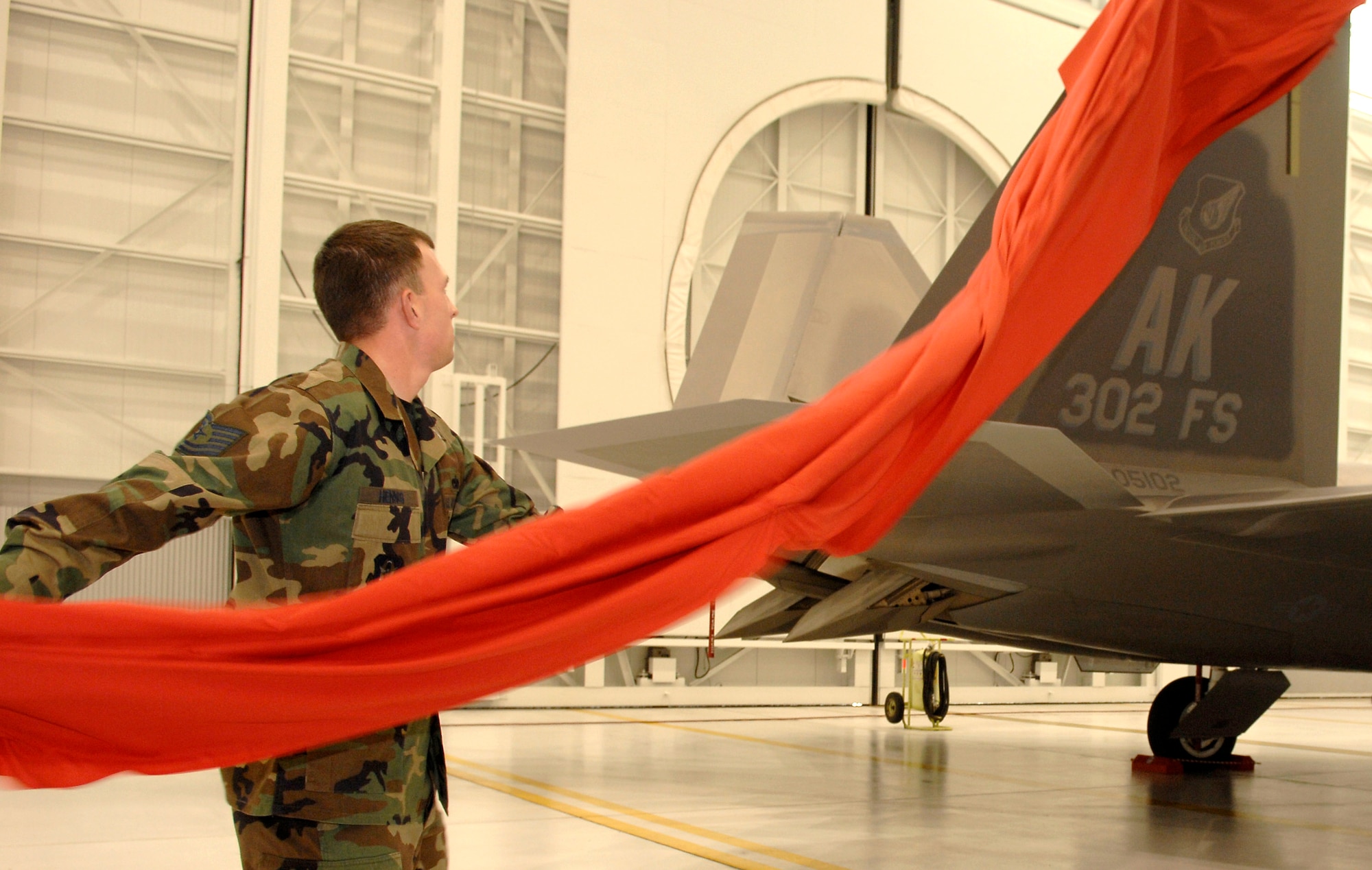 Tech. Sgt. Paul Hennig unveils the newly painted 302nd Fighter Squadron tail markings Oct. 2 following the 477th Fighter Group activation ceremony at Elmendorf Air Force Base, Alaska. The 477th FG, and its subsequent squadrons, are now the first and only Reserve F-22 Raptor unit in the Air Force. (U.S. Air Force photo by Senior Airman Garrett Hothan)