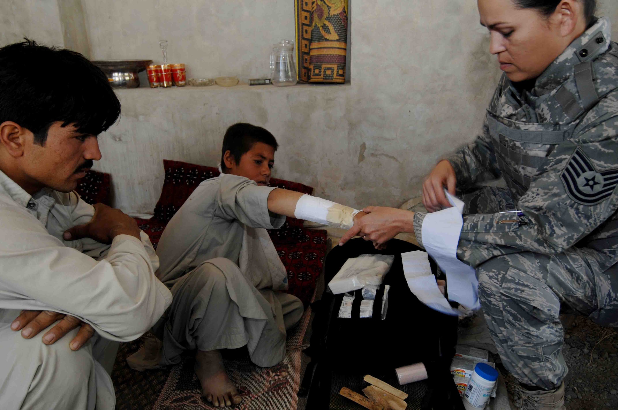 BAGRAM AIRFIELD, Afghanistan - Tech. Sgt. Joy Flumerfelt, a Squadron medical Element/Independent Medical Technician, with the 336 Expeditionary Fighter Squadron here, removes a makeshift splint from a boys broken arm.  His arm was then evaluated and resplinted  with better  materials, during a Medical Civil Action Project in a village outside of Bagram Airfield on Oct. 4, 2007.  (U.S. Air Force photo/Staff Sgt. Joshua T Jasper)