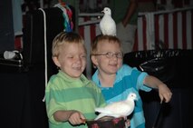 Two boys hold the doves that a magician pulled out of his top hat at the Air Force 60th anniversary event at Arnold Engineering Development Center’s Gossick Leadership Center Recreation Beach area. (Photo by David Housch)