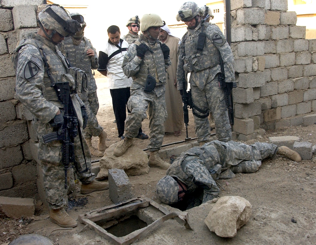 U.S. Army Sgt. 1st Class Joseph Kennedy and Sgt. Ryan Hill search a concealed hole in the front yard of a house during a cordon and search operation in Biaj, Iraq, Sept. 27, 2007. The soldiers are assigned to Bravo Troop, 9th Cavalry Regiment, 4th Brigade Combat Team, 1st Cavalry Division.