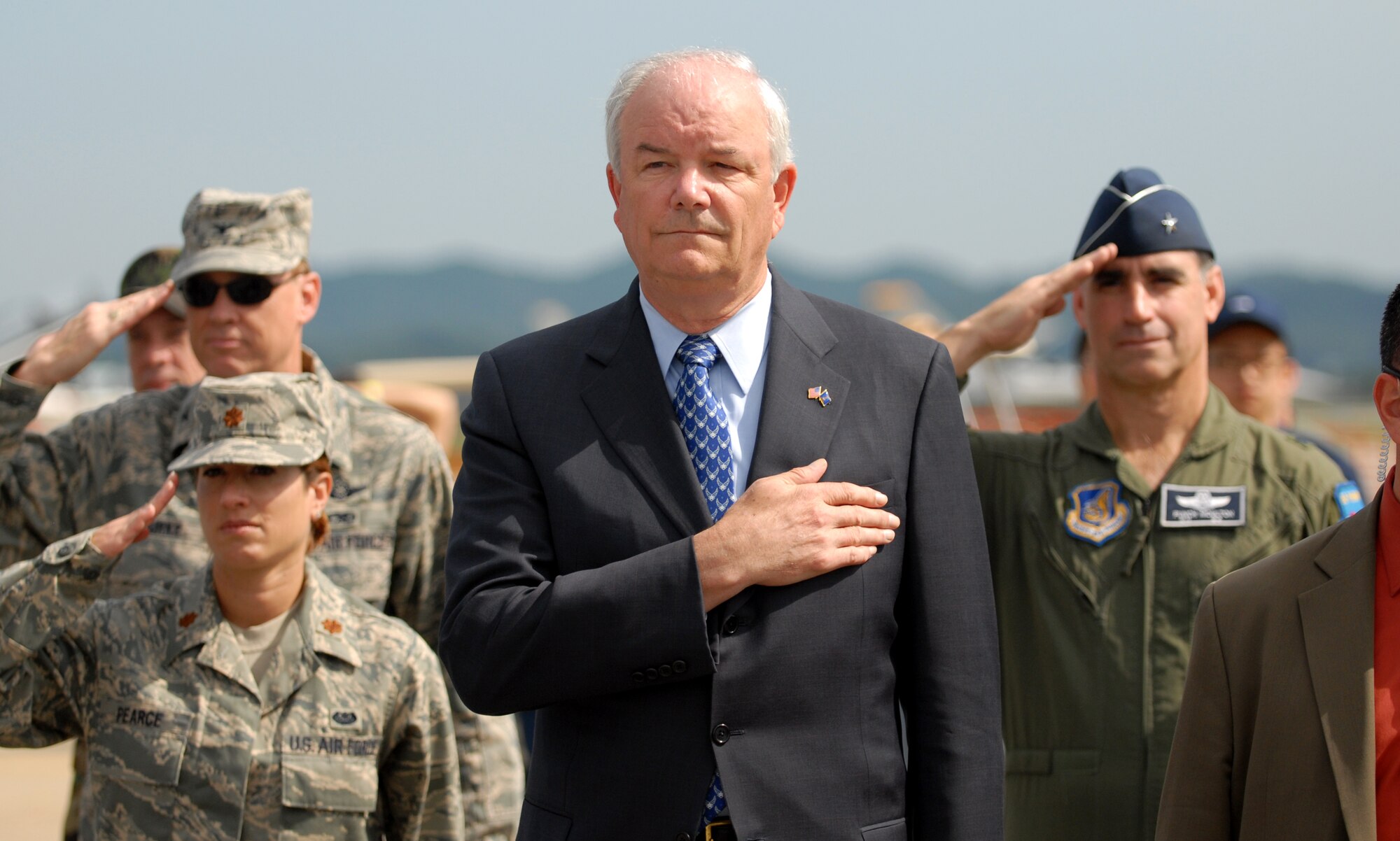 OSAN AIR BASE, Republic of Korea -- Secretary of the Air Force Michael W. Wynne, along with Col Darryl Burke, Maj Michelle Pearce and Brig Gen "Punch" Moulton, stands for the national anthem during opening ceremonies for Air Power Day. (Air Force photo by 1st Lt. John Ross)
