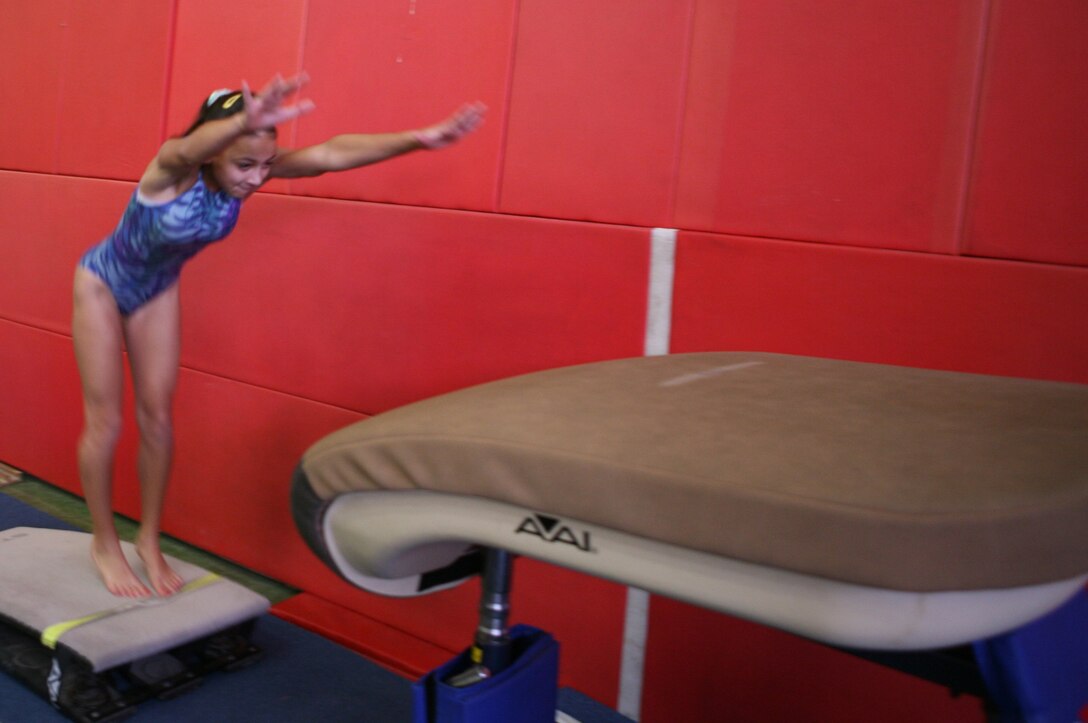 Colby Lock, a gymnast at the Youth Activities Center, jumps off the vaulting buck and prepares herself to flip over the pad and land feet-first on a mat on the other side. Lock and the other gymnasts have practice four times a week for about three hours each session.