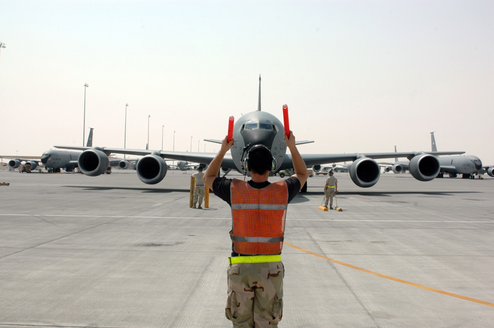 SOUTHWEST ASIA -- Senior Airman Mike McGovern , 340th Aircraft Maintenance Squadron, marshalls a KC-135 to its parking spot while Tech. Sgt. Robert Wade and Senior Airman Neal Sicardstand byto place chocks around the tires of the aircraft. (U.S. Air Force photo/Staff Sgt. Jason Barebo)