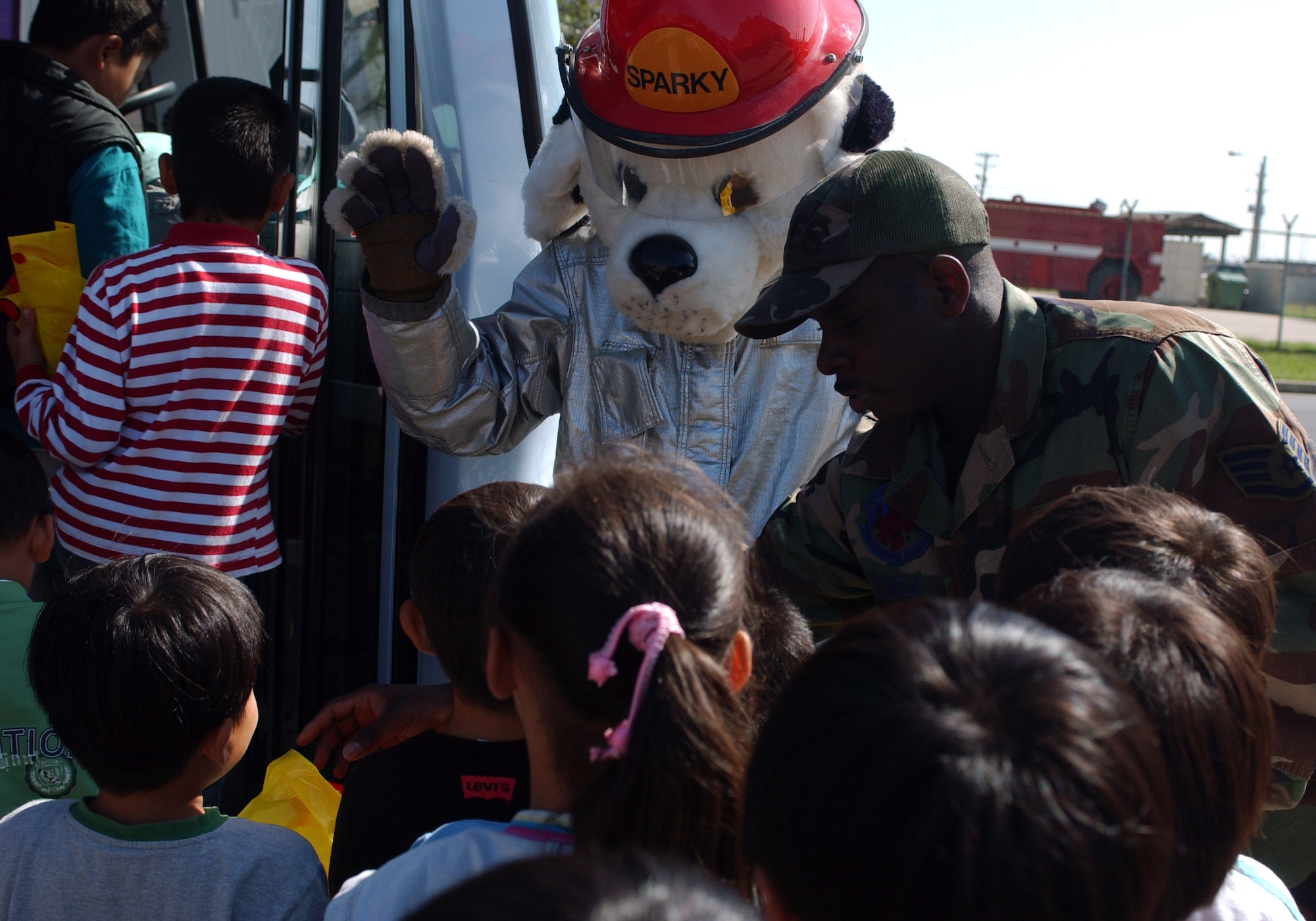 KUNSAN AIR BASE, South Korea -- Staff Sgt. Floydzell Kimble, 8th Civil Engineer firefighter, and Sparky, hand out gift bags as children depart from their visit to the fire station here Oct. 9.  The children were from several schools throughout Gunsan City, South Korea. They toured the base fire station as part of Fire Prevention Week. (U.S. Air Force photo/Senior Airman Steven R. Doty)                      