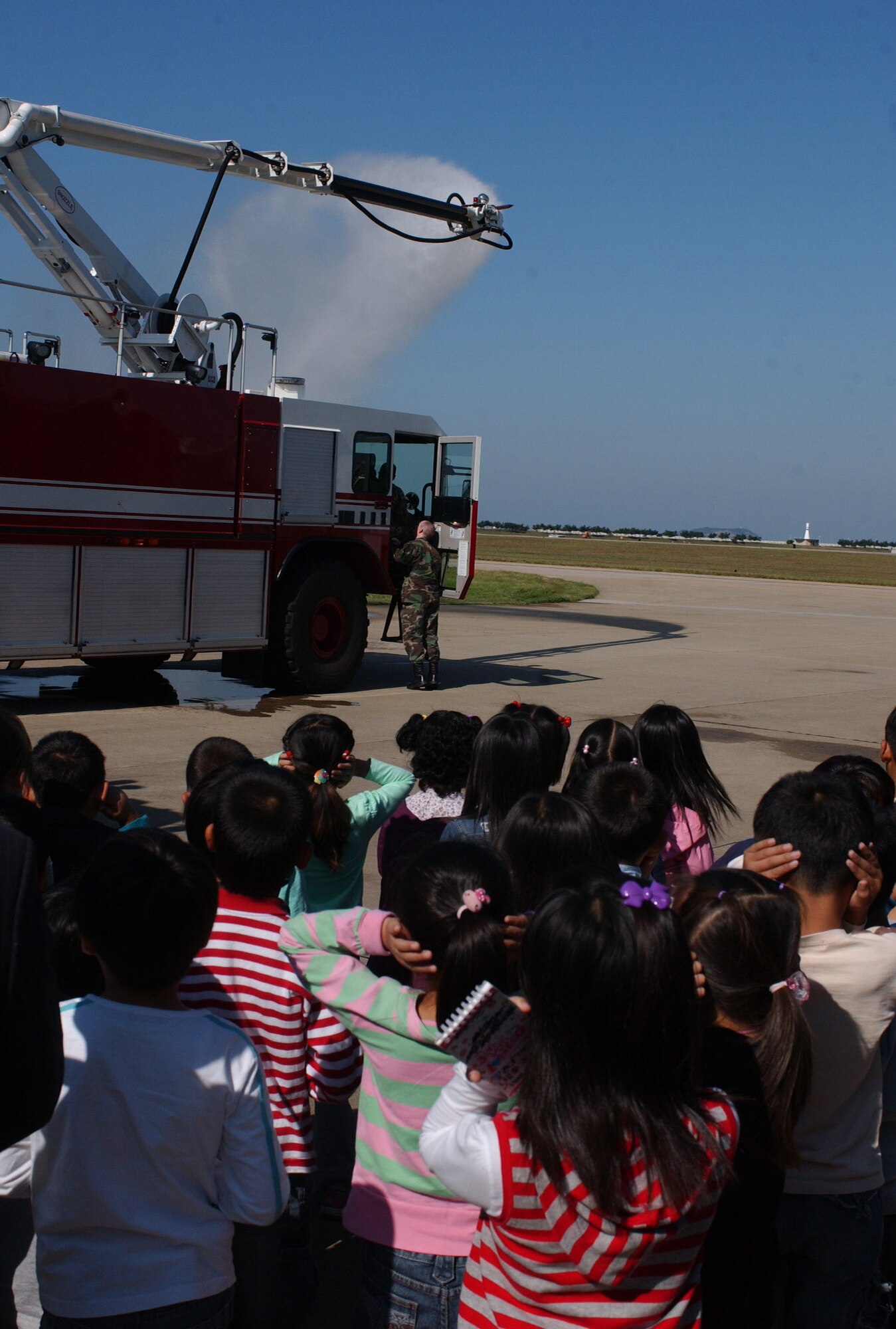 KUNSAN AIR BASE, South Korea -- Korean students watch a tanker shoot out water during their visit to the fire department here Oct. 9. The children were from several schools throughout Gunsan City, South Korea. They toured the base fire station as part of Fire Prevention Week. (U.S. Air Force photo/Senior Airman Steven R. Doty)