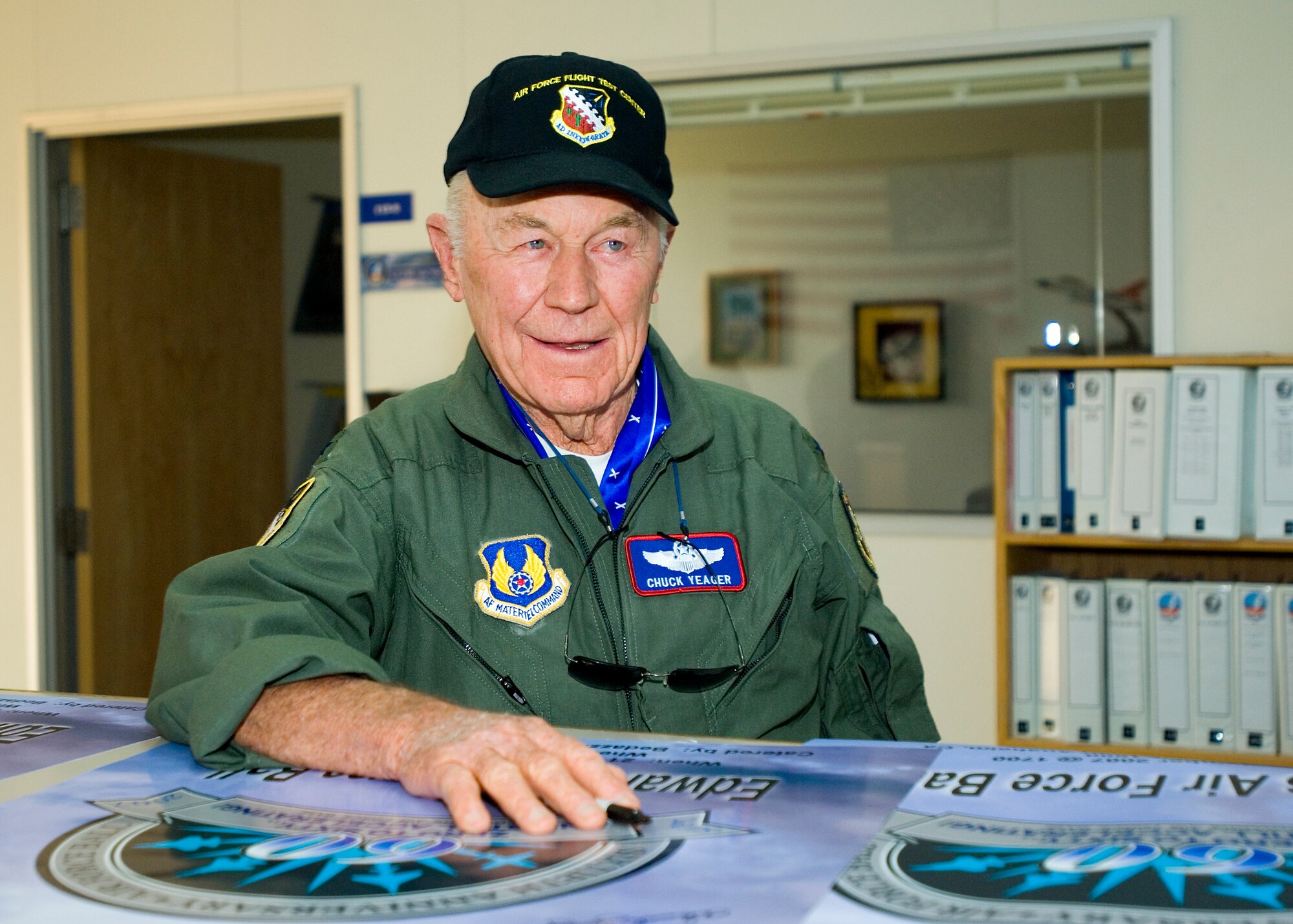 Retired Brig. Gen. Chuck Yeager pauses for a moment while autographing several Edwards Air Force Ball posters at Test Operations here Sept. 21. General Yeager flew an F-16 to Mach 1 at the Air Force Ball and produced a sonic boom commemorating his first supersonic flight 60 years earlier. (Photo by Mike Cassidy)