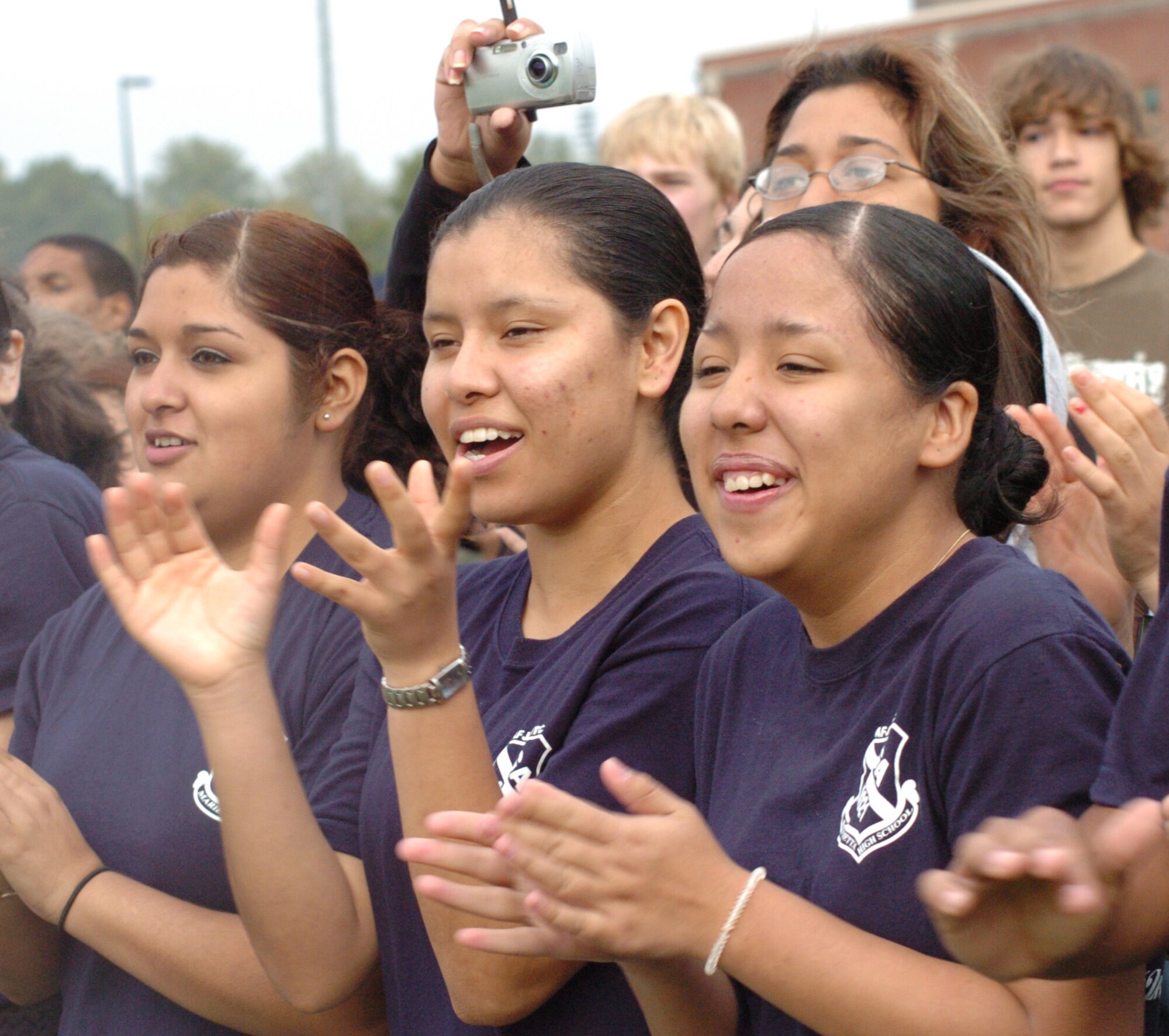 Marietta High School Air Force JROTC cadets (left to right) Airman Basic Delangel Lorena, Airman Basic Maria Barcenas, and Airman Basic Diana Quiroz cheer the helicopter pararescue demonstration by the 301st Rescue Squadron, Patrick AFB, Fla. The aircraft used in the demonstration is the HH-60 Pavehawk. "This demonstration was an alternate infiltration/exfiltration exercise," said Master Sgt. Steve Johnson, the Pavehawk's flight engineer. The exercise demonstrated the capability of the pararescueman to retrieve a survivor by hoist.  The rescue demonstration is part of the "Heritage to Horizons" 60th Anniversary celebration for Air Force Week Atlanta.(U.S. Air Force photo/Master Sgt. Stan Coleman)