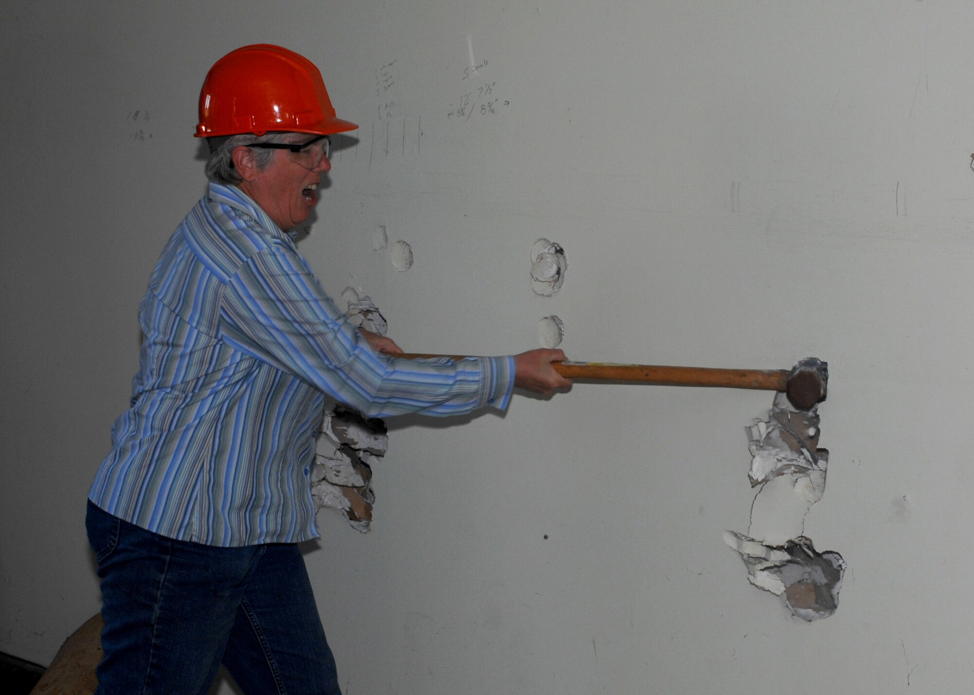 WHITEMAN AIR FORCE BASE, Mo. -- Julie Mayer, thrift shop volunteer, rips into the drywall of the shop's former home in Bldg. 1435, just south of the 509th Bomb Wing headquarters, Oct. 9. The building, condemned since 1993, is currently being demolished. The thrift shop moved out of the building in April and set up operations in the former base library location next to the Airman and family readiness center. (U.S. Air Force photo/Tech. Sgt. Samuel A. Park)