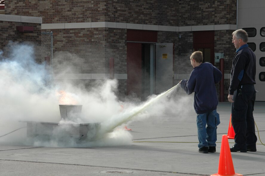 Children are coached on how to effectivly use a fire extinguisher during an open house at the fire department Oct. 6. The open house was preceeded by a Fire Prevention Week Parade. This year's theme is Practice your Escape Plan.
(U.S. Air Force photo/Airman 1st Class Kimberly Moore Limrick)